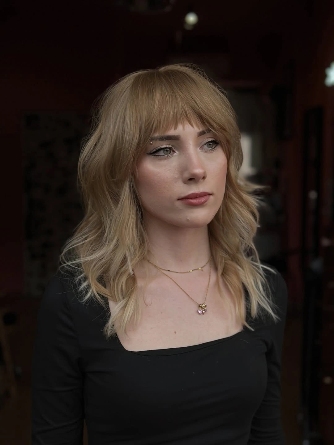 Blonde shoulder-length shag with full fringe and outward-curving layers