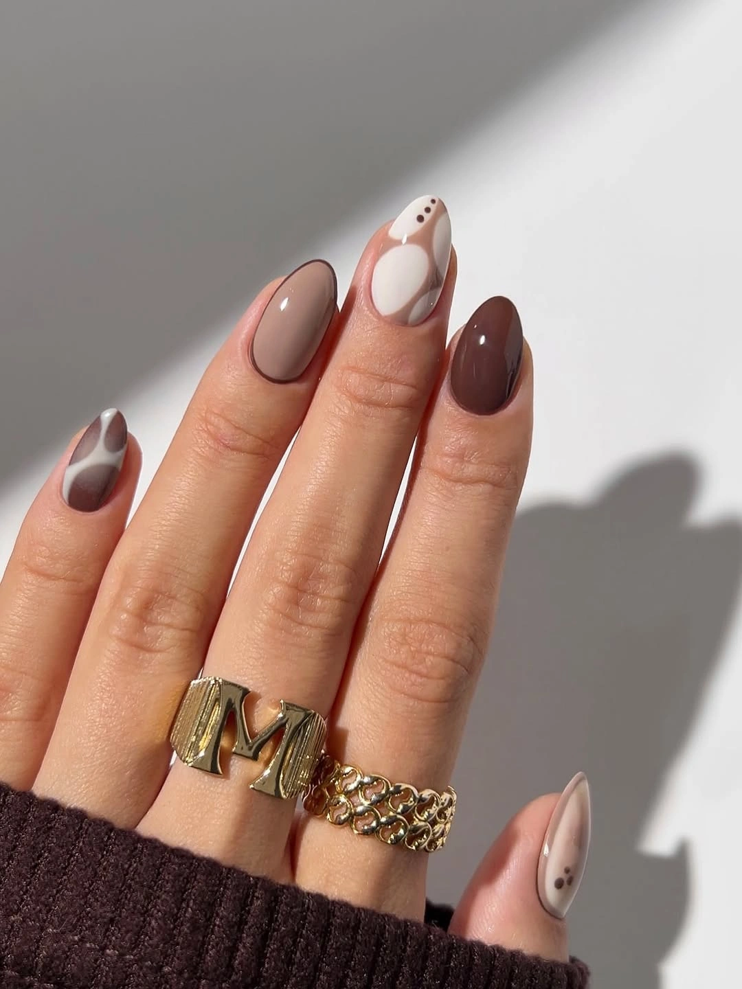 Almond nails in glossy brown, taupe, cream and dotted abstract shapes