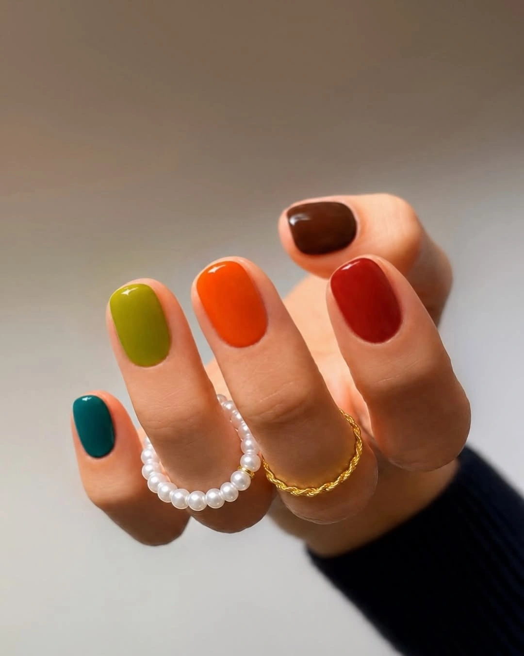 Short rounded nails in teal, olive, orange, red and brown