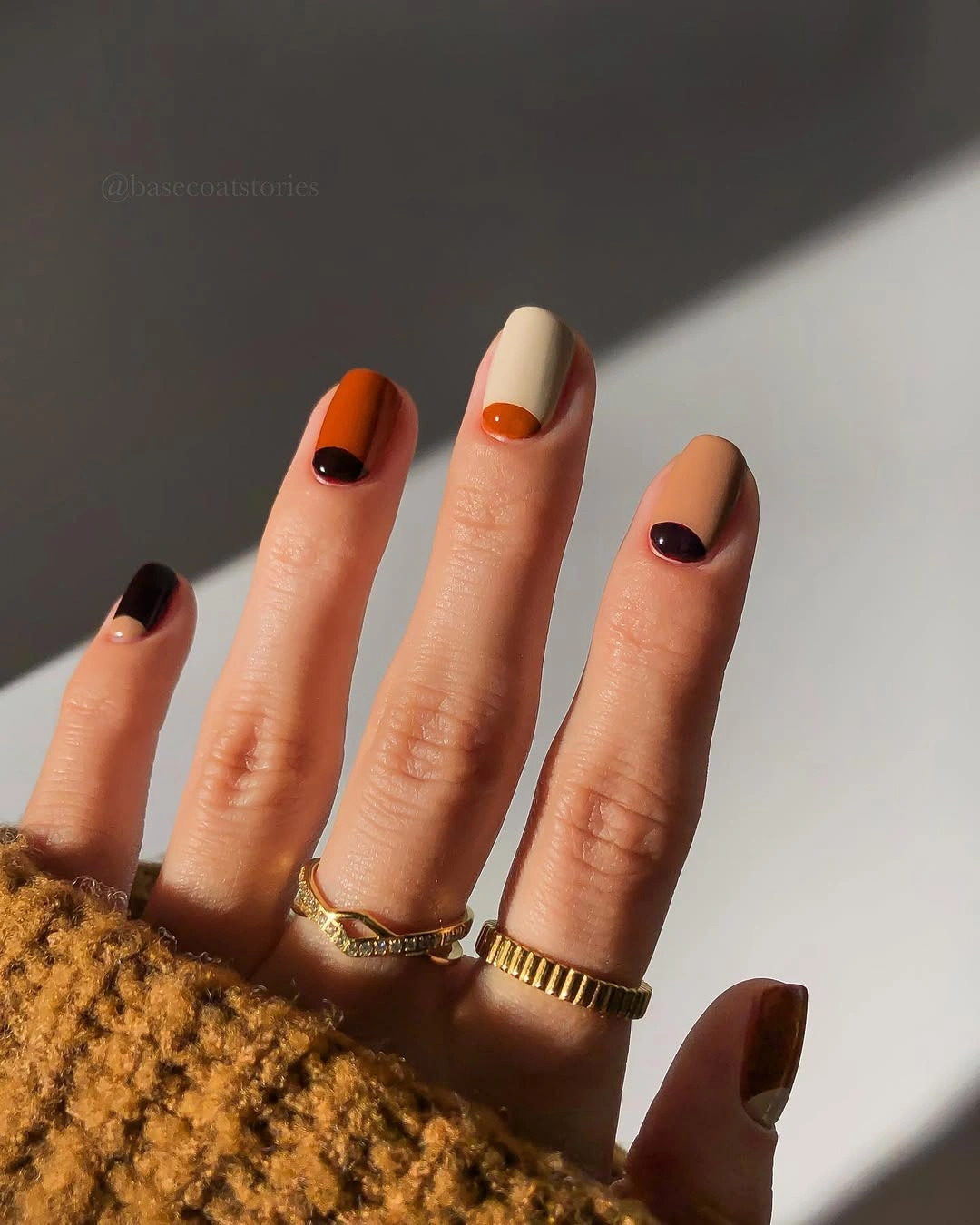 Short rounded nails with tan, orange, brown and dark oval accents
