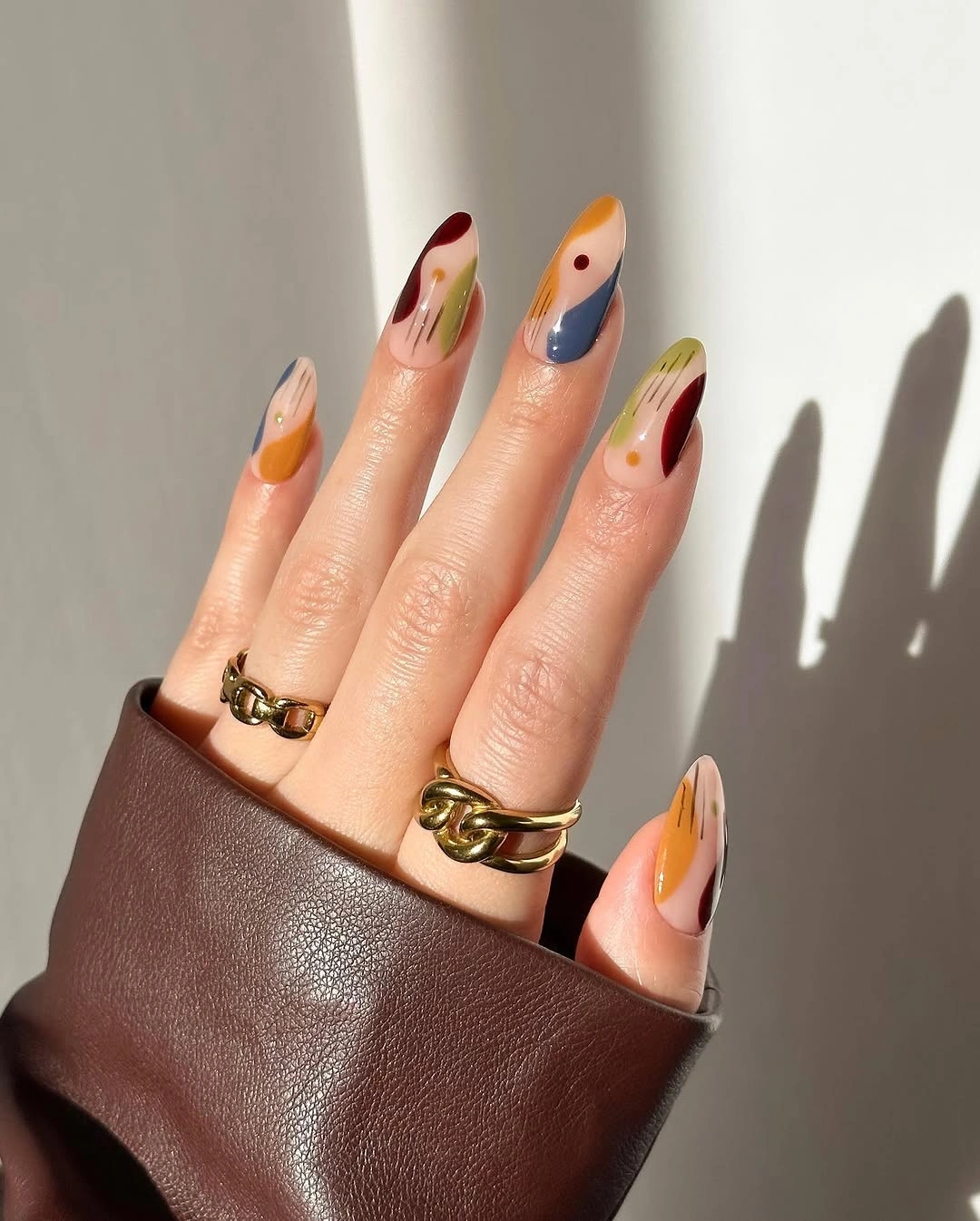 Almond nails with orange, blue, burgundy and olive abstract shapes