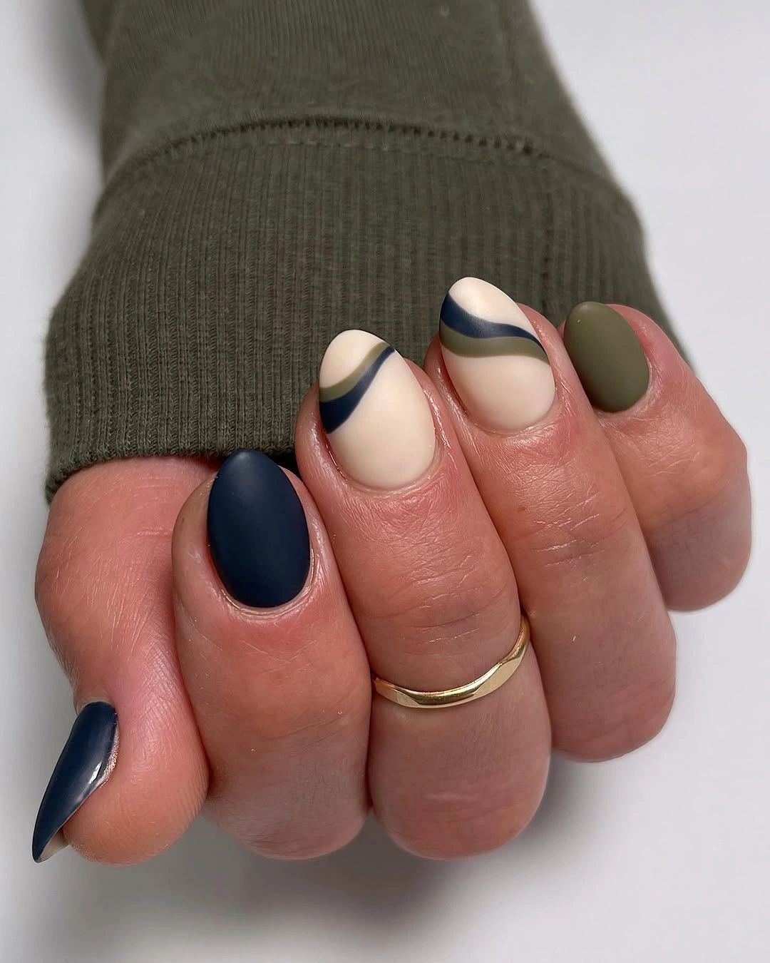 Short almond nails with matte navy, cream and green waves