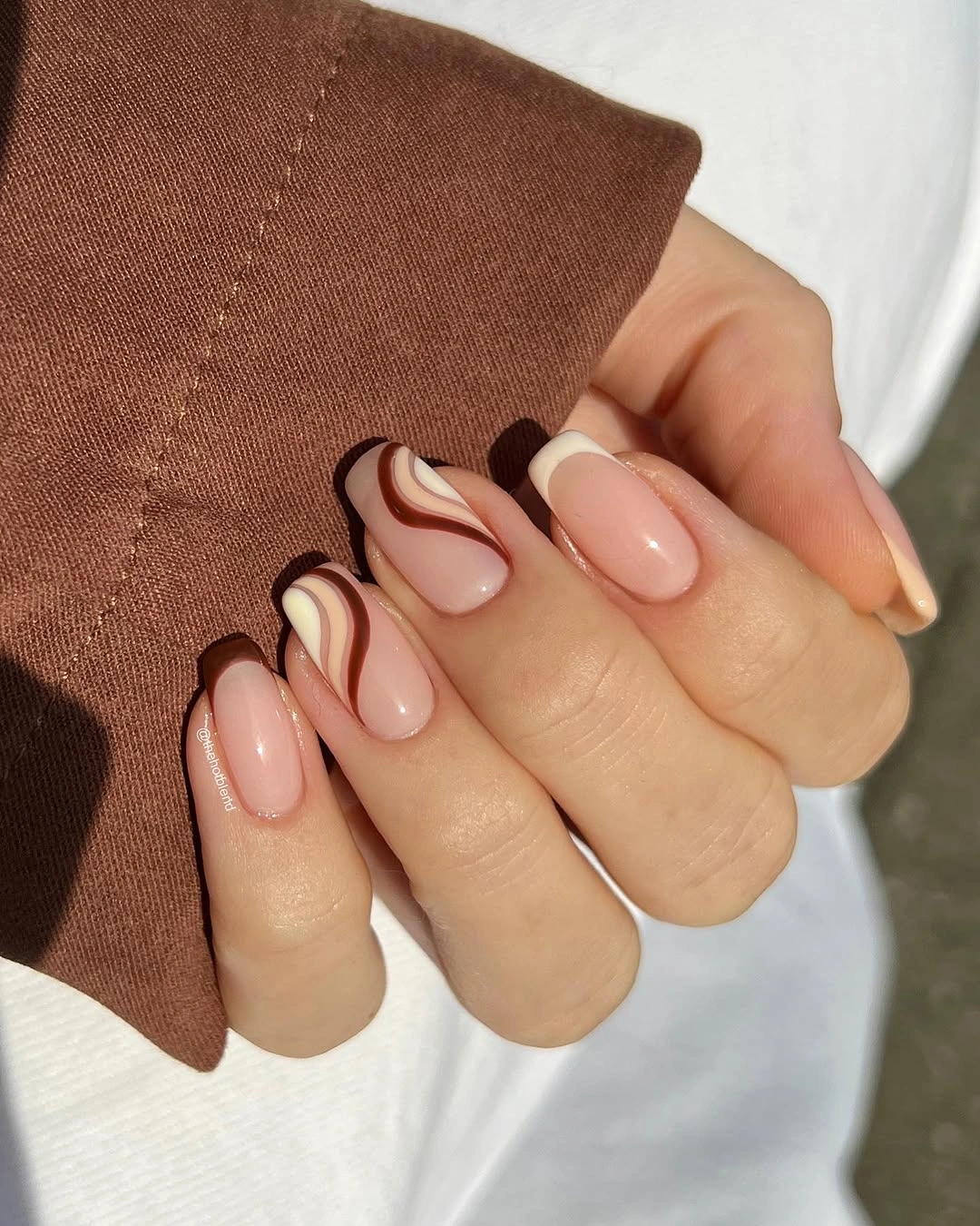 Short almond nails with blush bases and chocolate side swirls