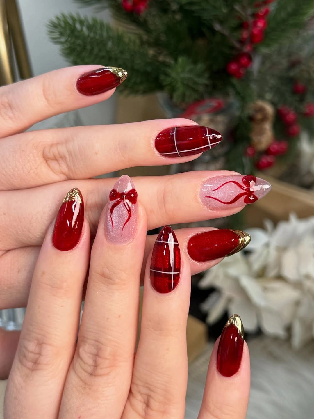 Glossy red almond nails with plaid and bow accents