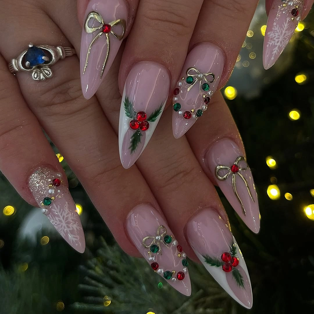 Long pointed pink nails with gold-toned bows and gems