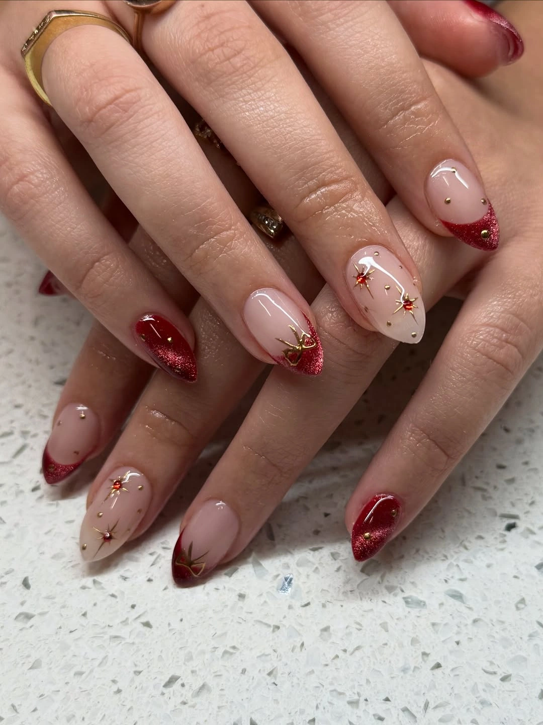 Almond nude nails with red glitter tips and star accents