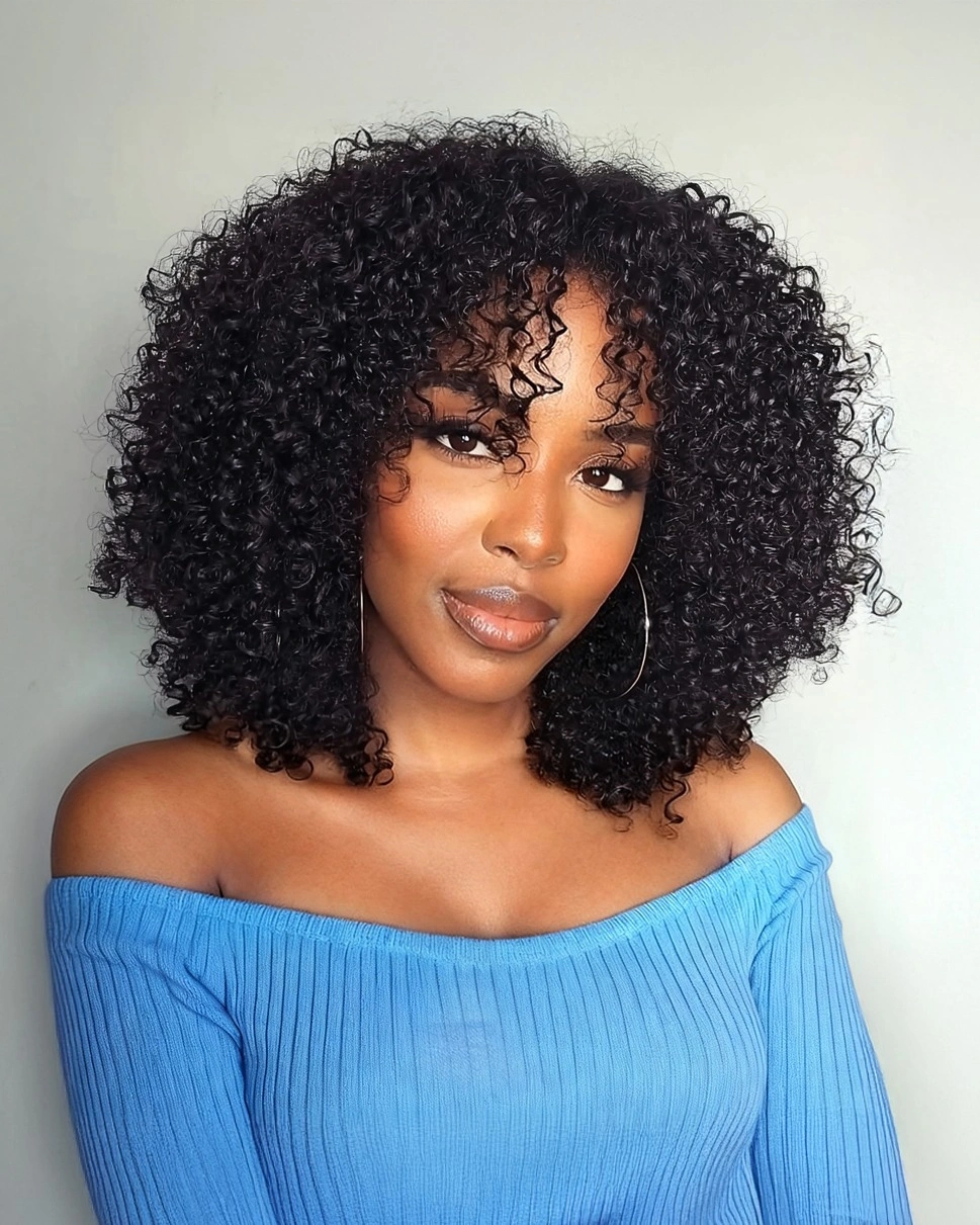 Full rounded black curls with hoop earrings and blue top