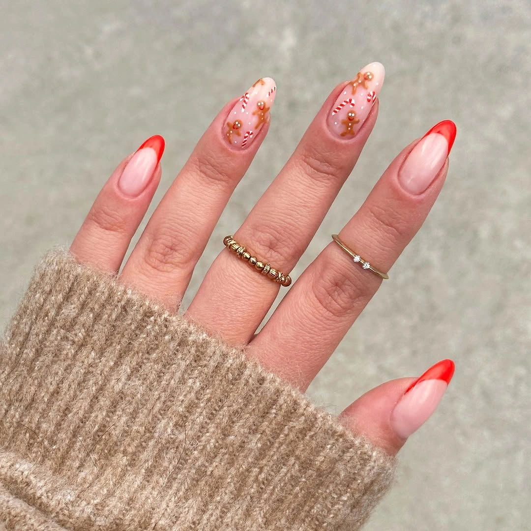 Long almond nails with red tips and gold-toned accents