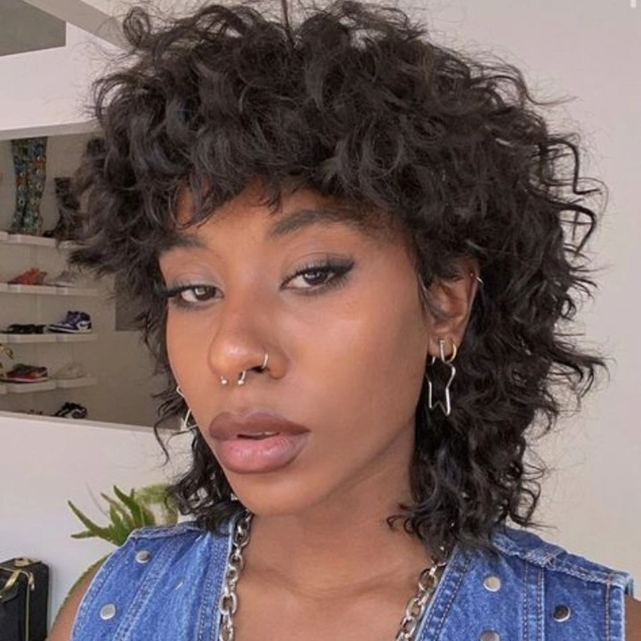 Short tousled dark layers with cropped fringe and denim vest