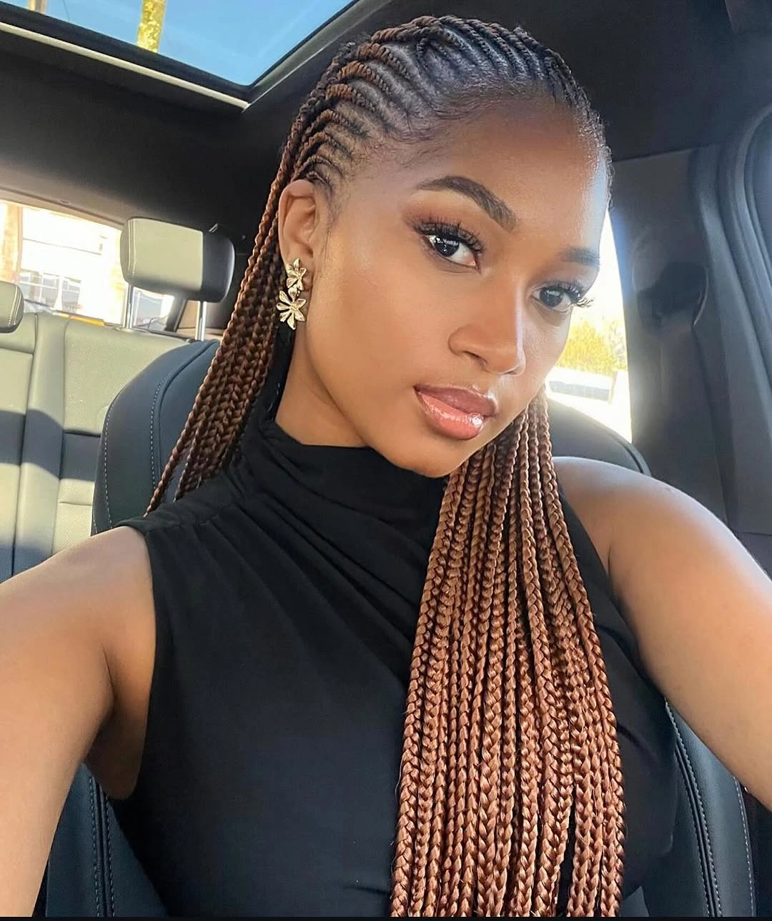 Long copper-brown braids with neat rows and star earrings