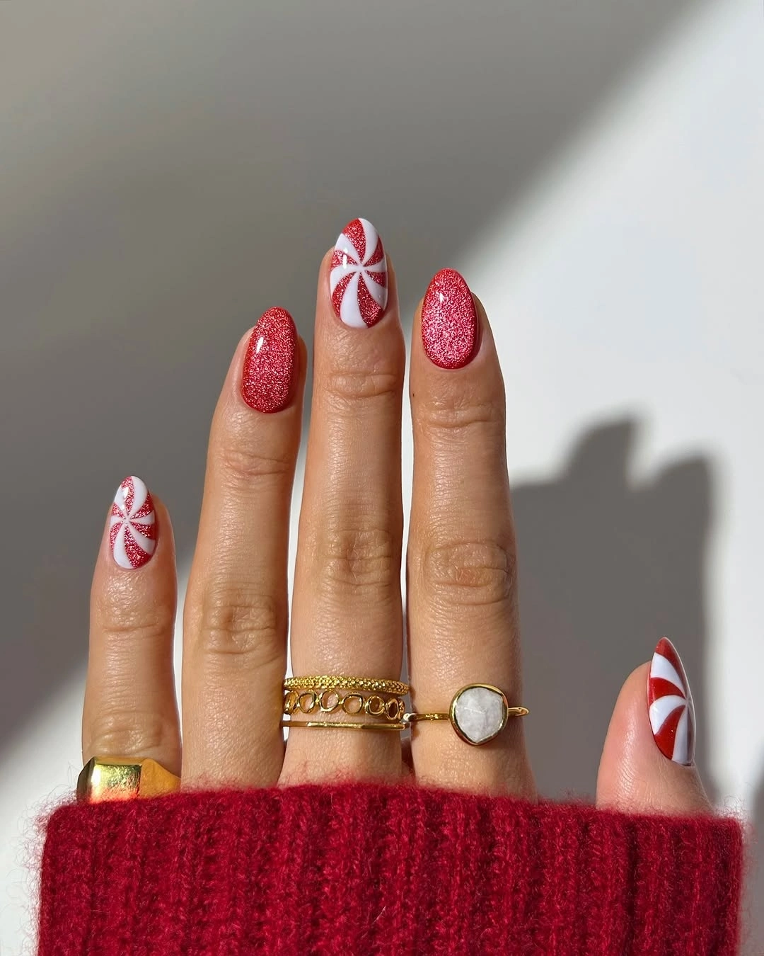 Short red glitter nails with peppermint swirl accents
