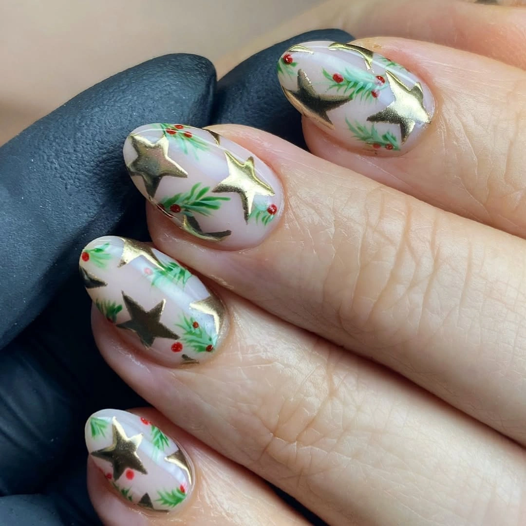 Pale rounded nails with gold stars and pine sprigs