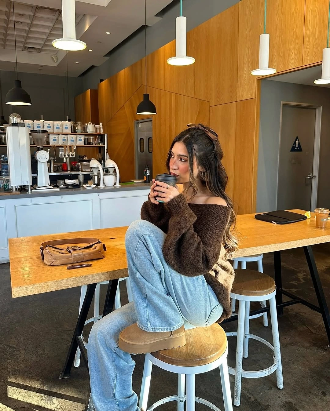 Brown off-shoulder sweater with wide light jeans and hair bow