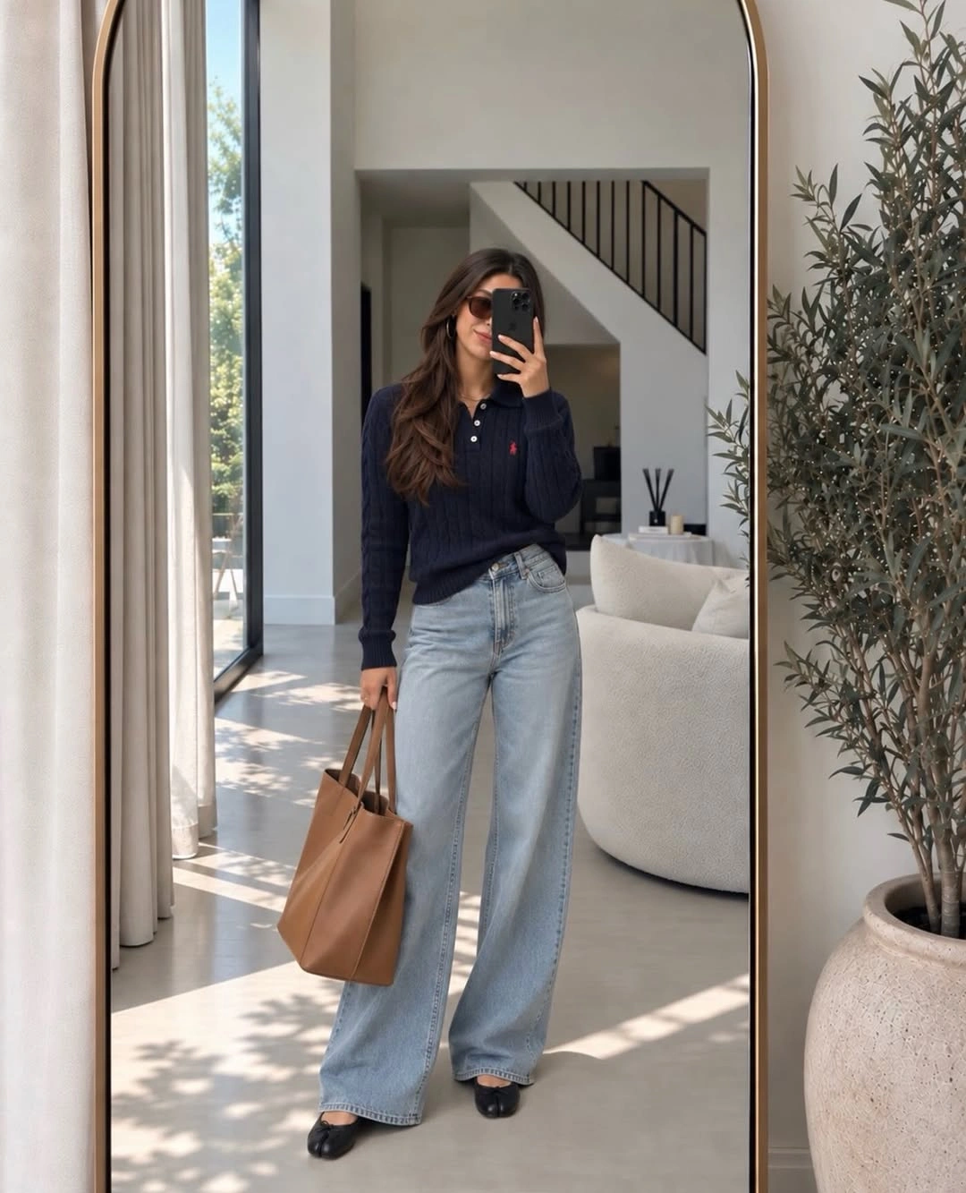 Navy collared sweater with light wide jeans and tan tote