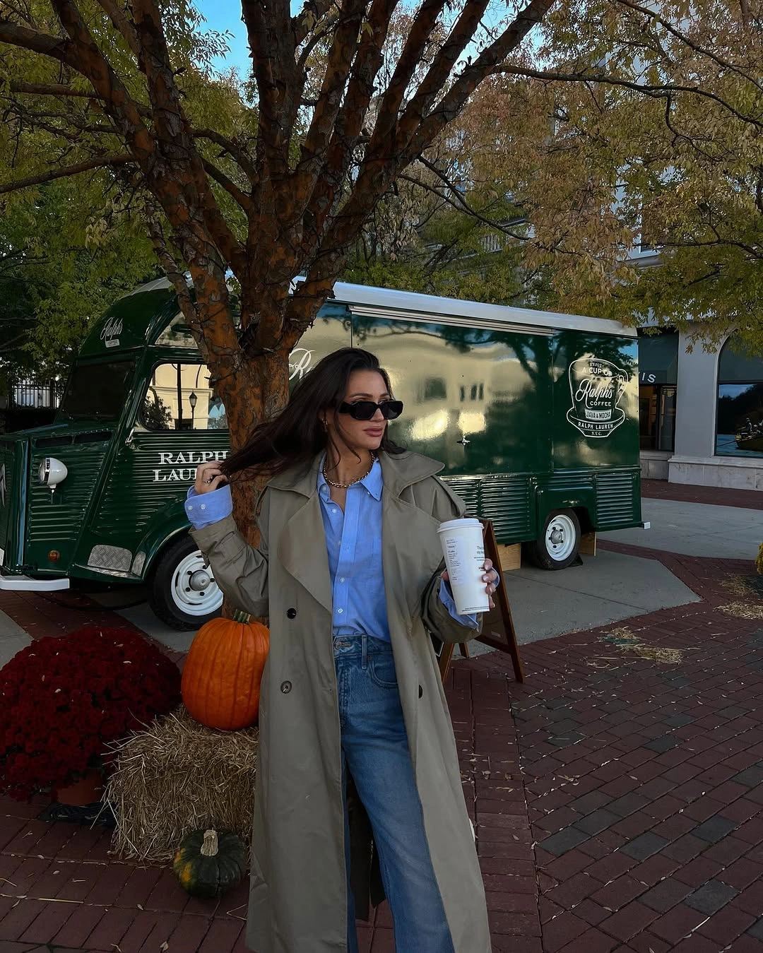Beige trench coat with blue shirt jeans and sunglasses