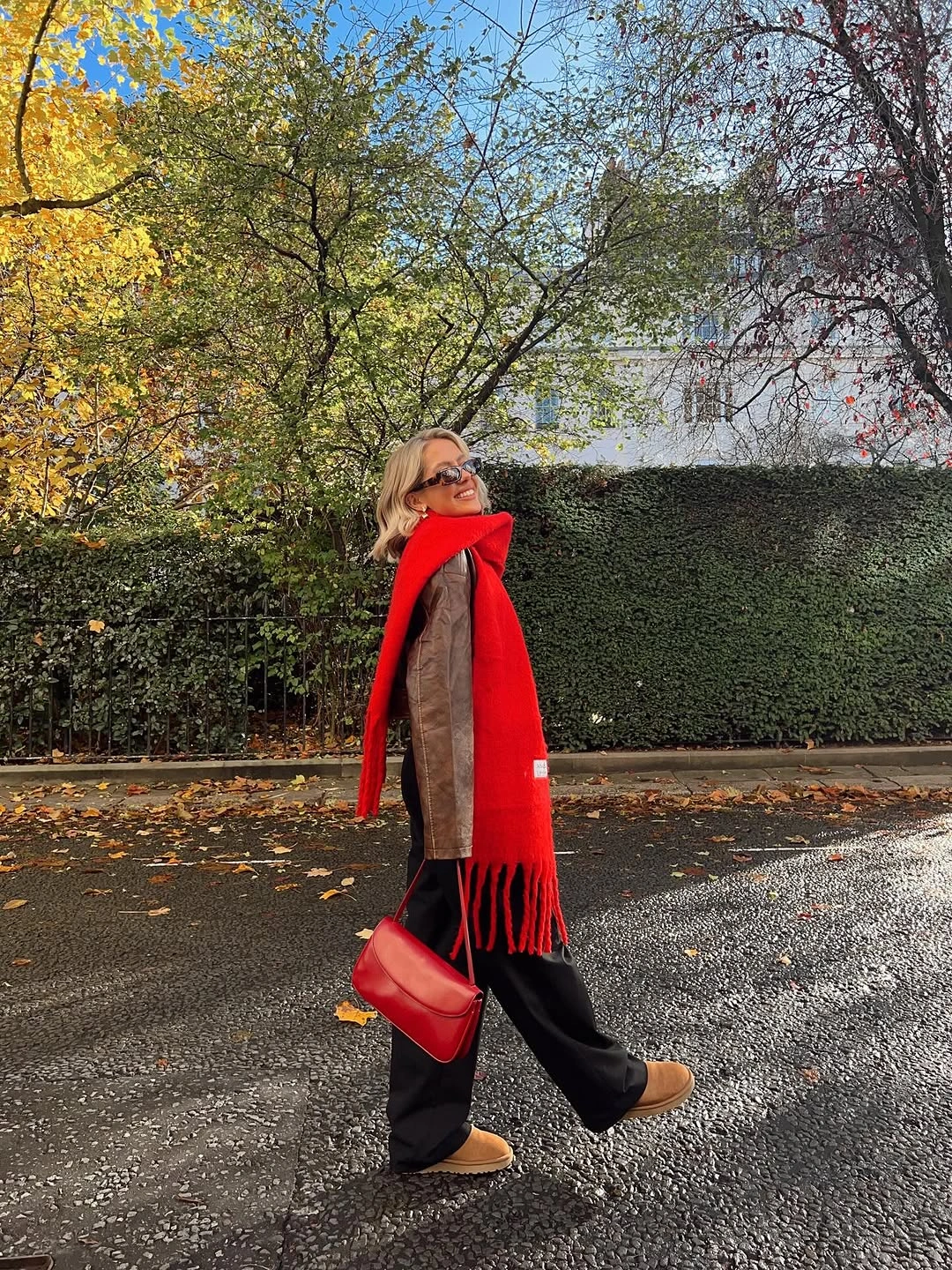 Red scarf with brown jacket black trousers and red bag