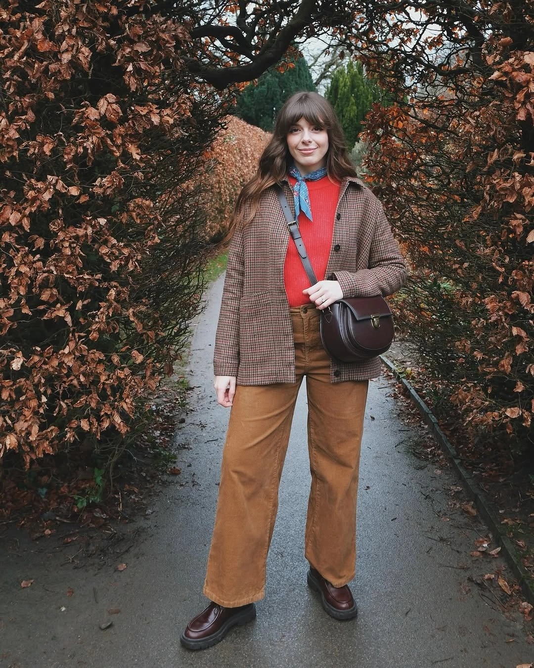 Checked brown jacket red top tan trousers and blue scarf
