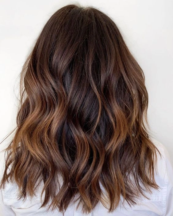 Shoulder-length chocolate waves with caramel-cinnamon ribbons