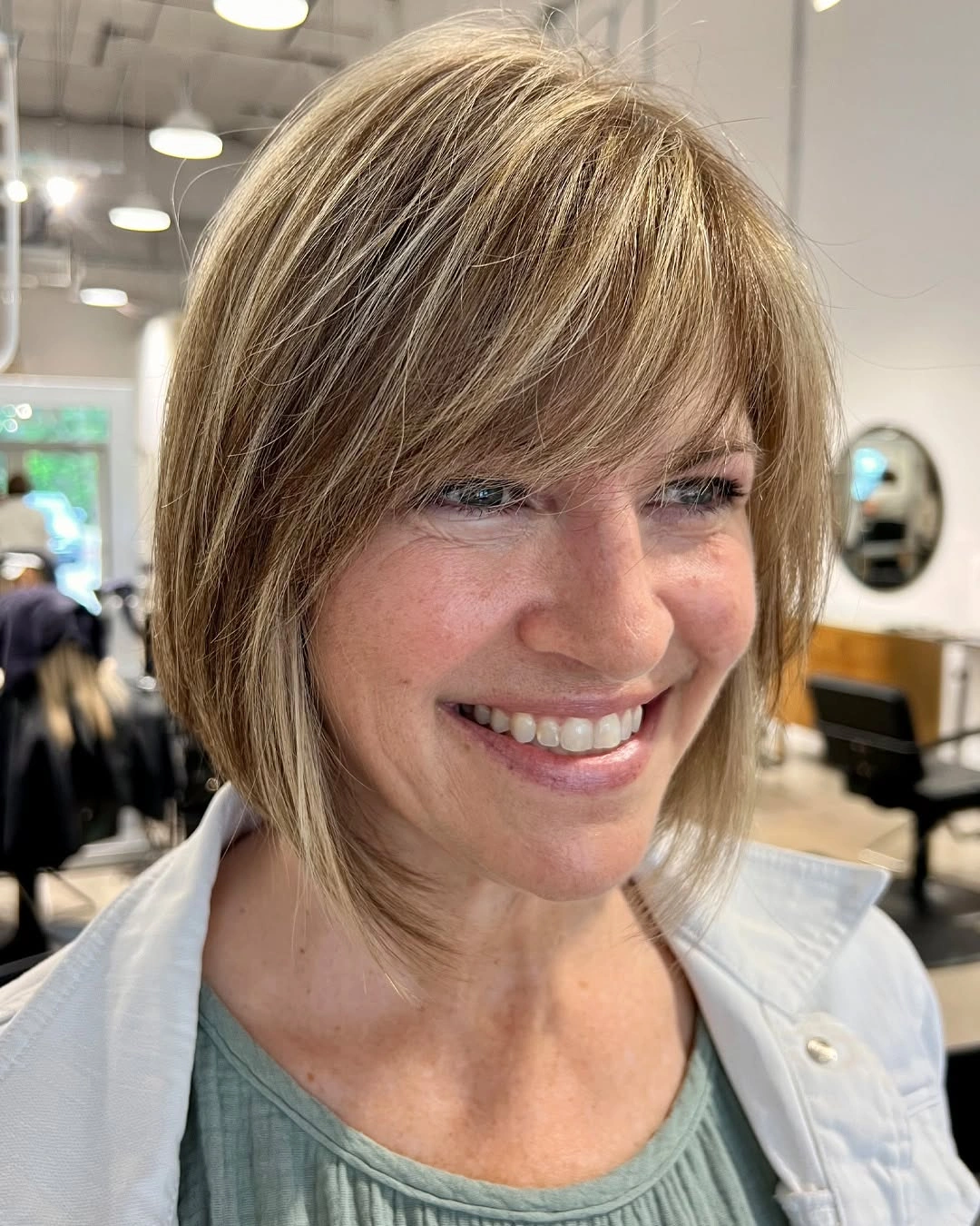 Light brown layered bob with side-swept bangs and tapered ends