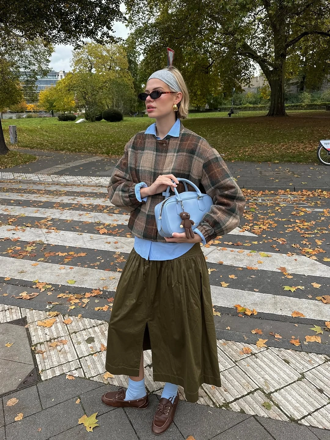 Cropped plaid jacket over blue shirt with olive skirt and brown shoes