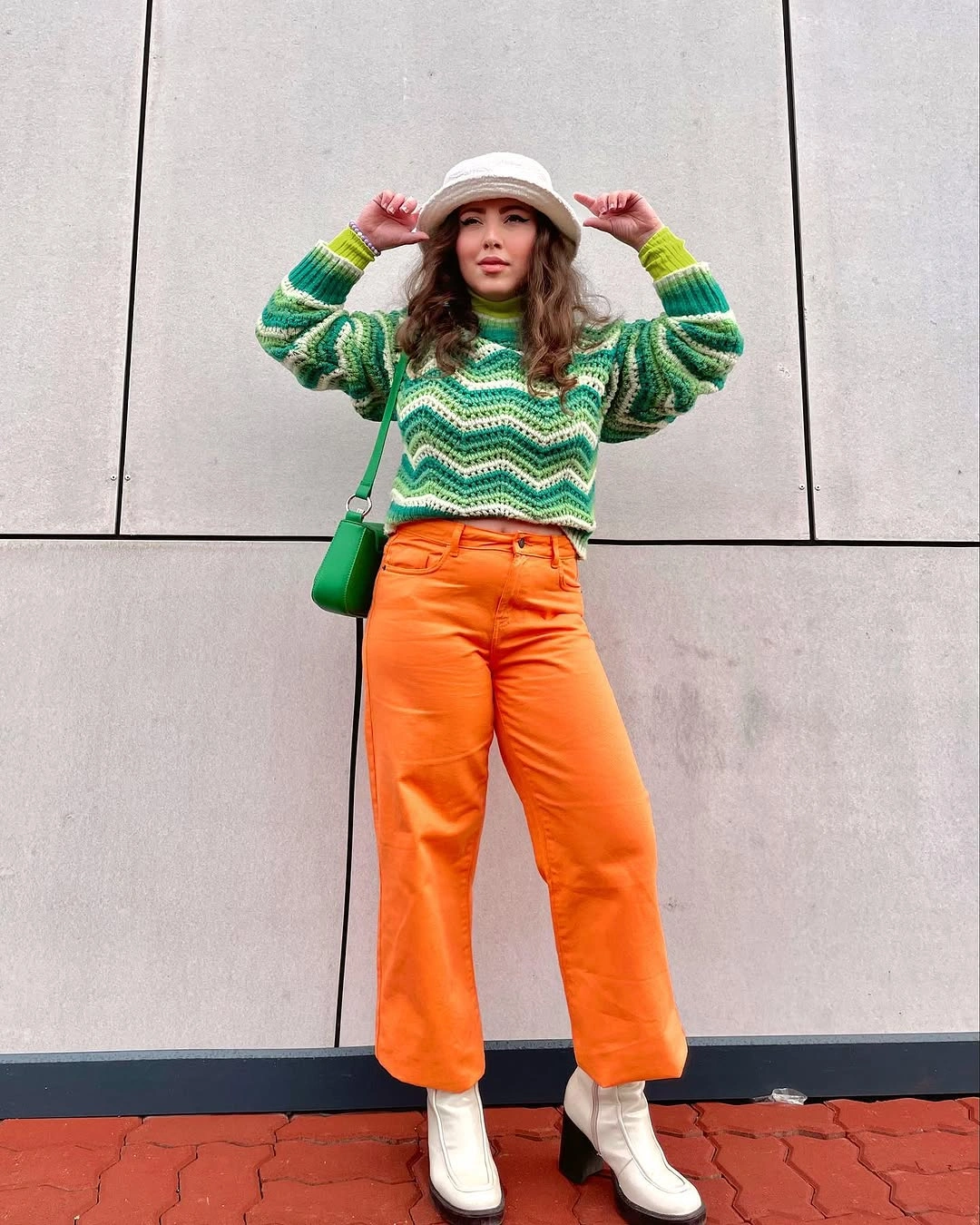 Green wavy sweater with orange trousers and white boots