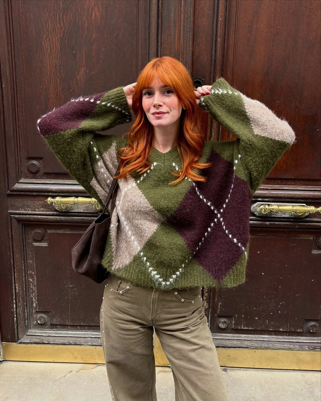 Oversized green argyle sweater with muted trousers and brown bag