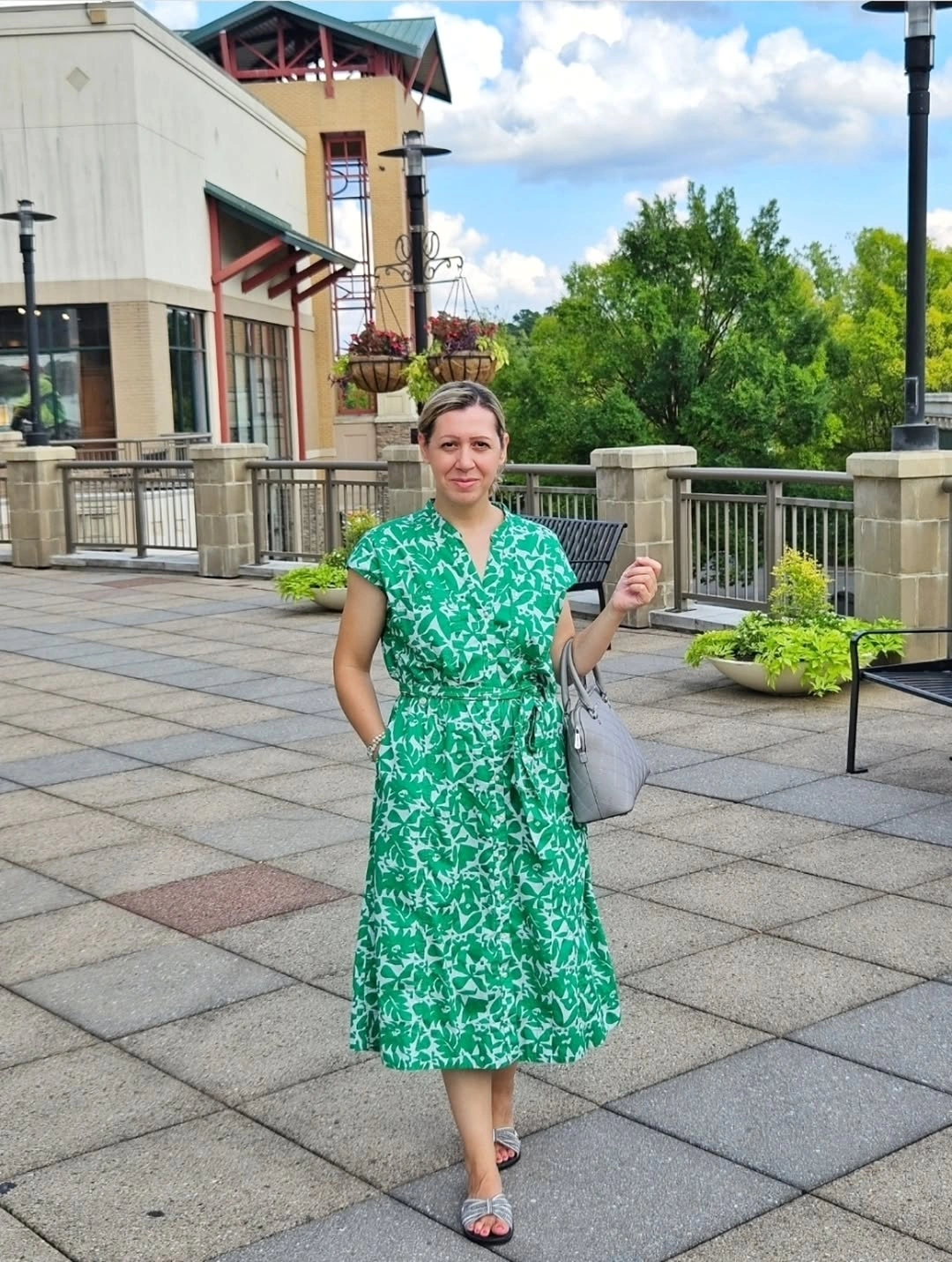 Woman in green patterned dress with gray shoulder bag