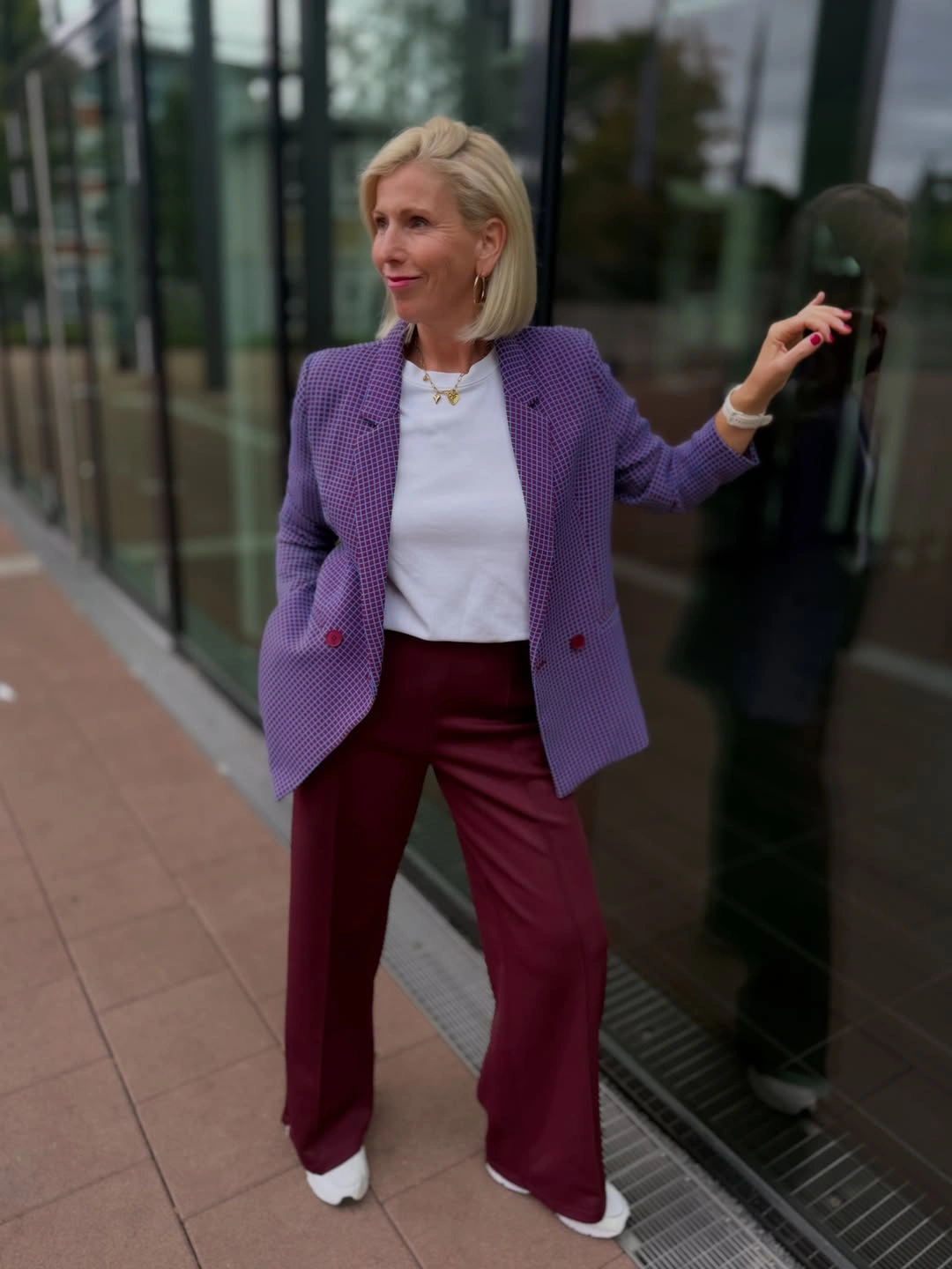 Woman wearing purple blazer burgundy trousers and white tee