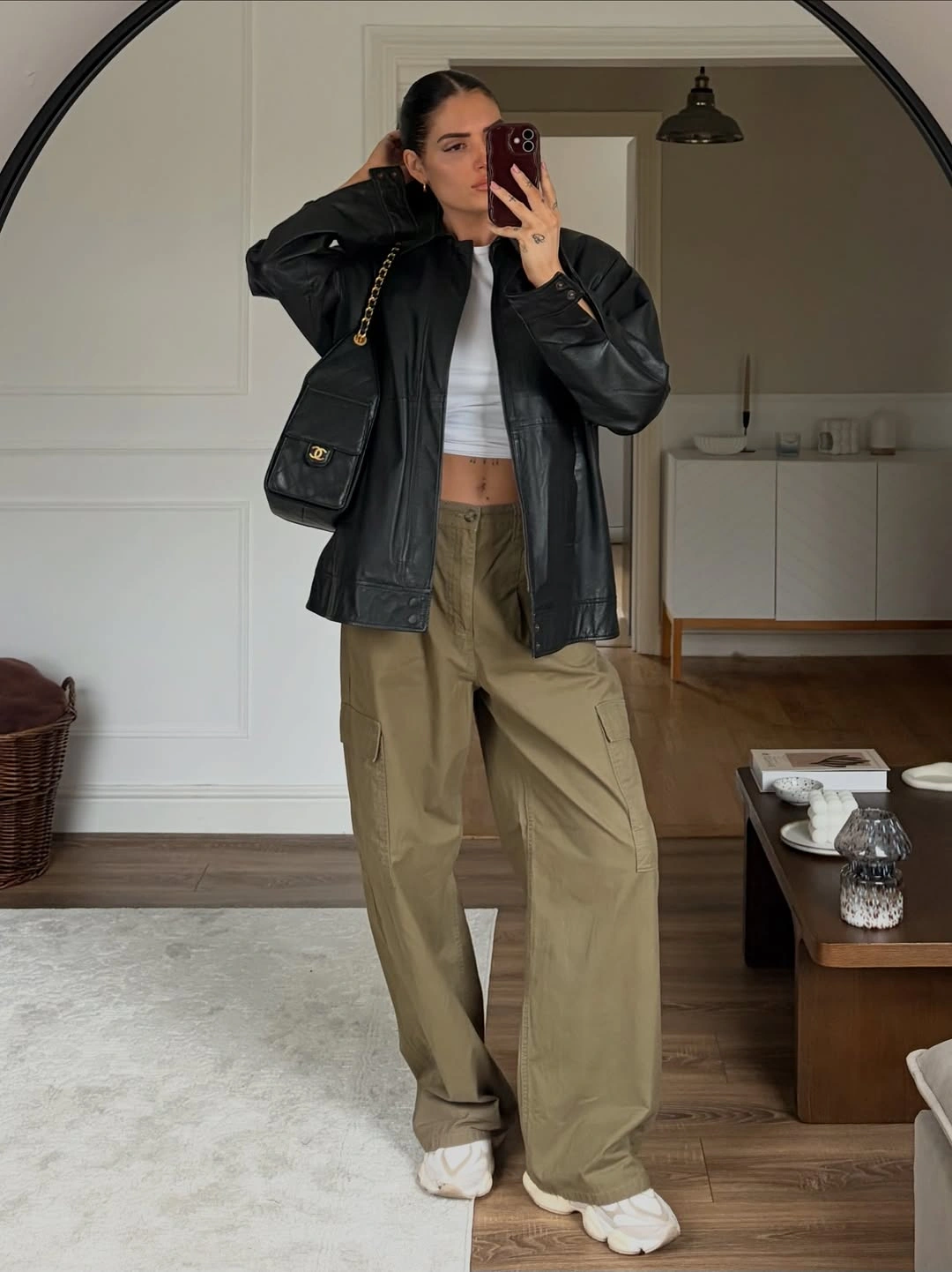 Woman in black leather-look jacket olive cargo pants and sneakers