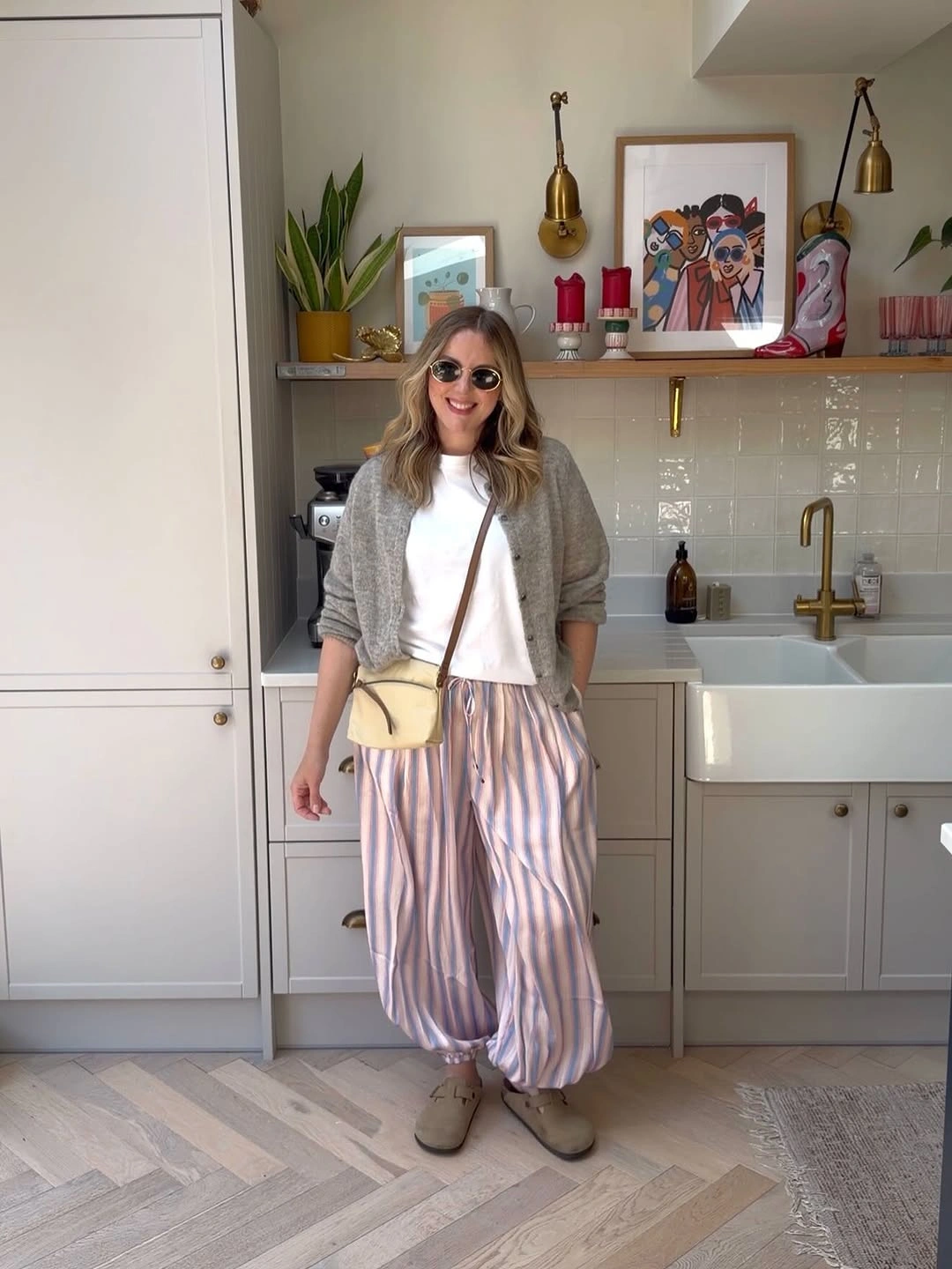 Woman in gray cardigan striped trousers and crossbody bag