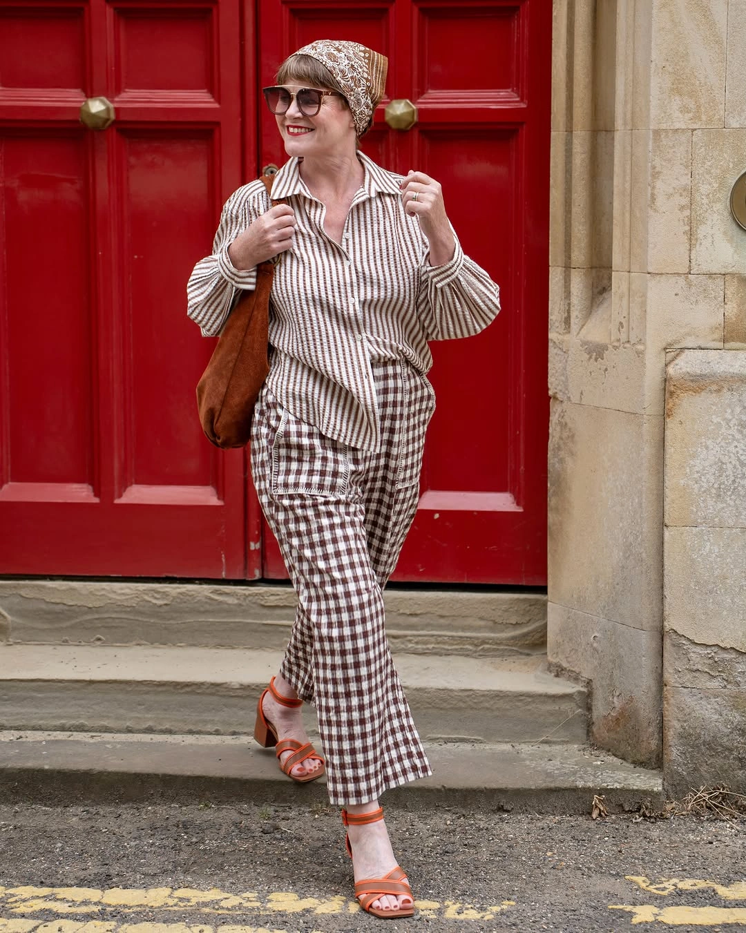 Woman in striped shirt checked trousers and patterned headscarf