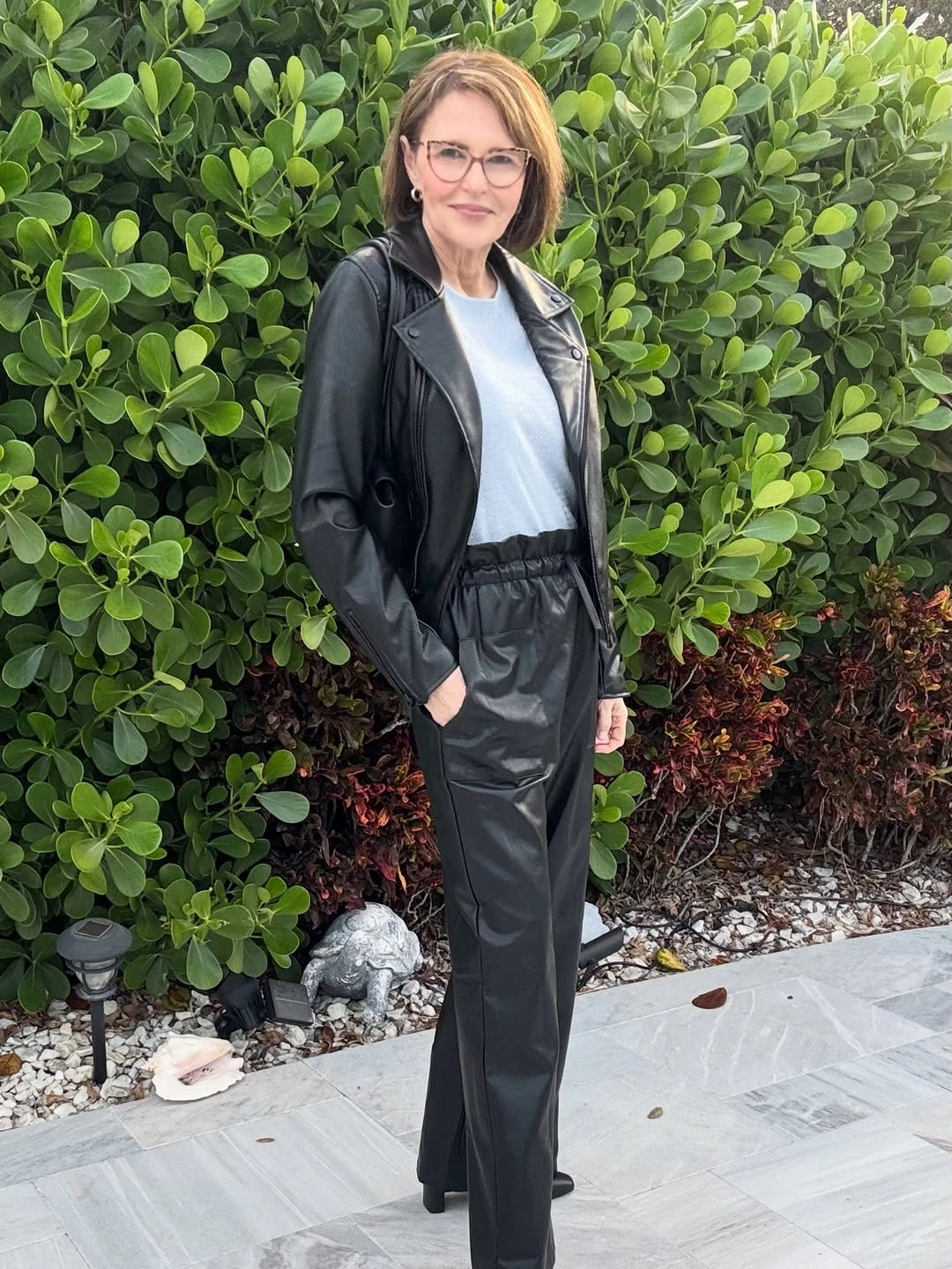 Woman in black leather-look jacket trousers and white top