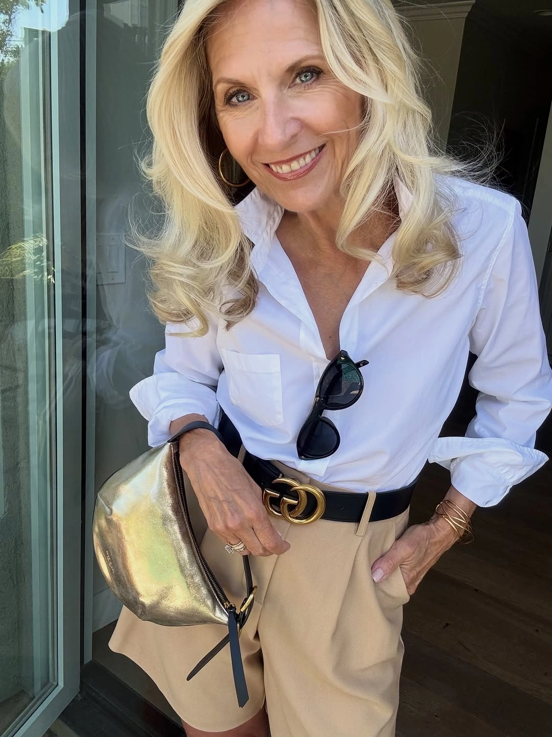 Woman in white shirt beige trousers and metallic bag