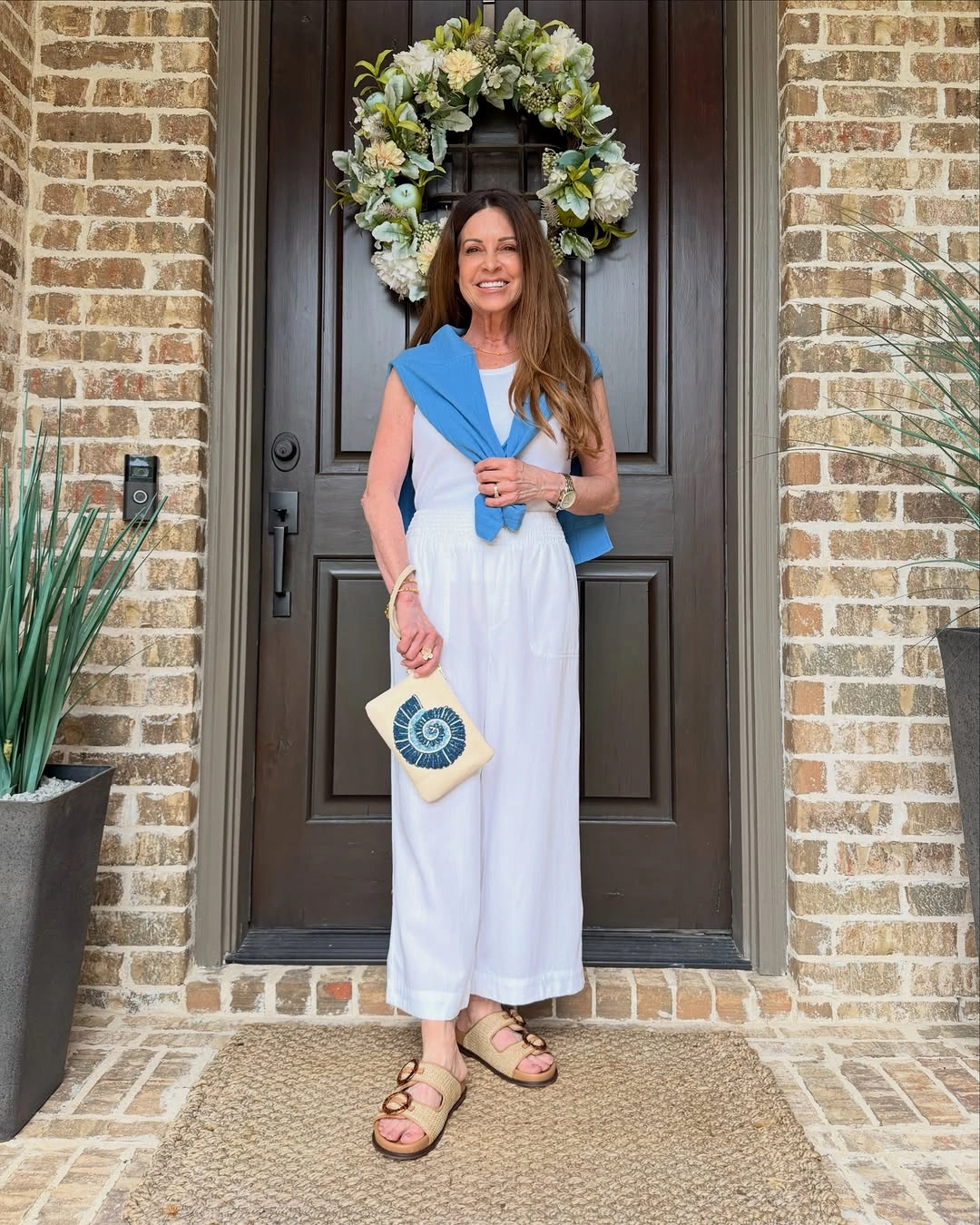 Woman in white wide leg outfit with blue sweater