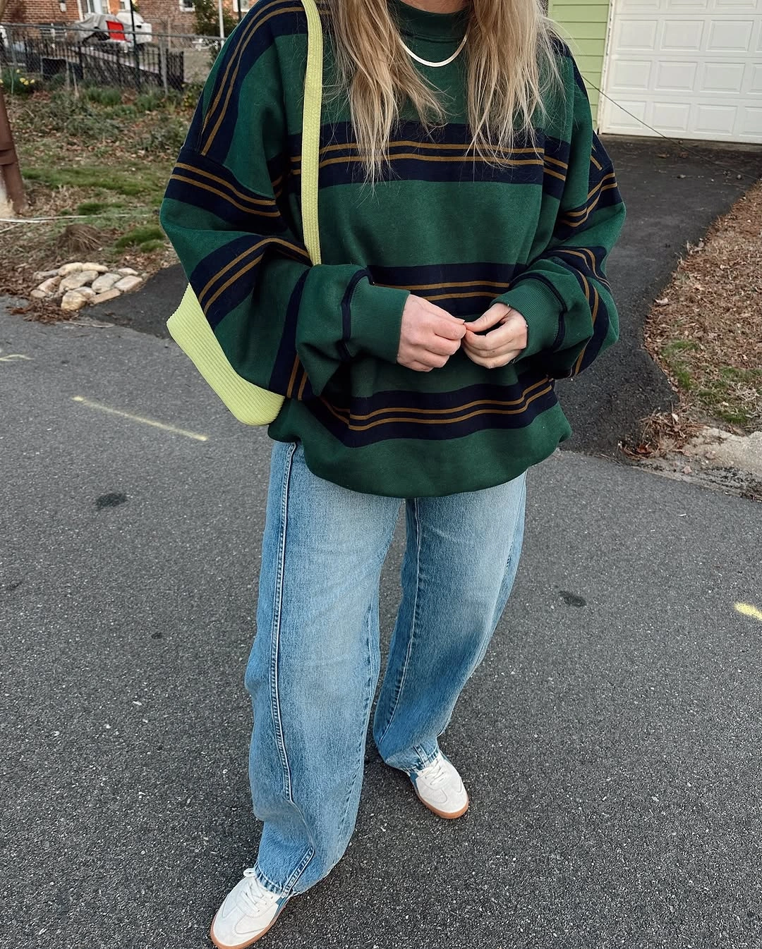 Green striped sweatshirt with pale jeans and bright shoulder bag