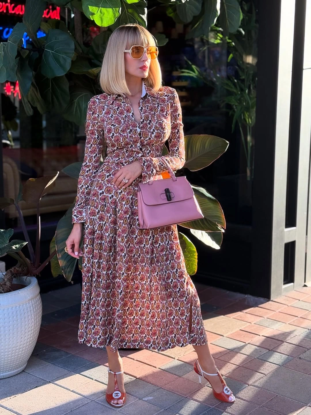 Patterned midi dress with pink handbag and orange sunglasses