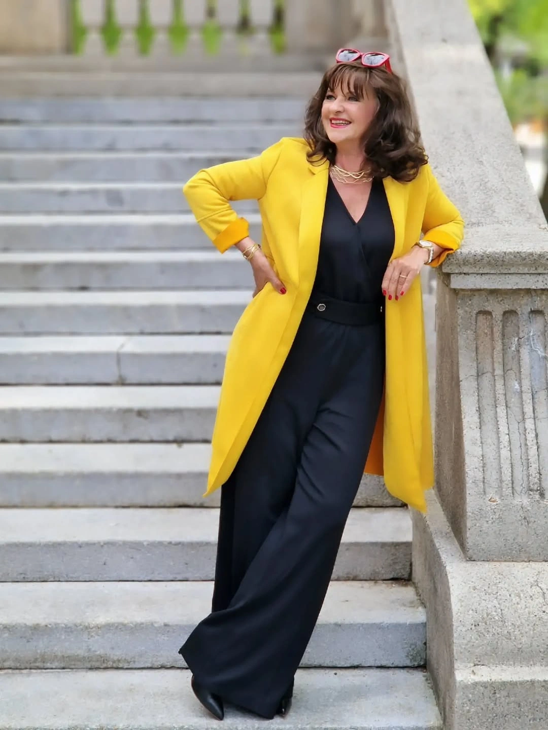 Yellow long coat over black V-neck top and trousers
