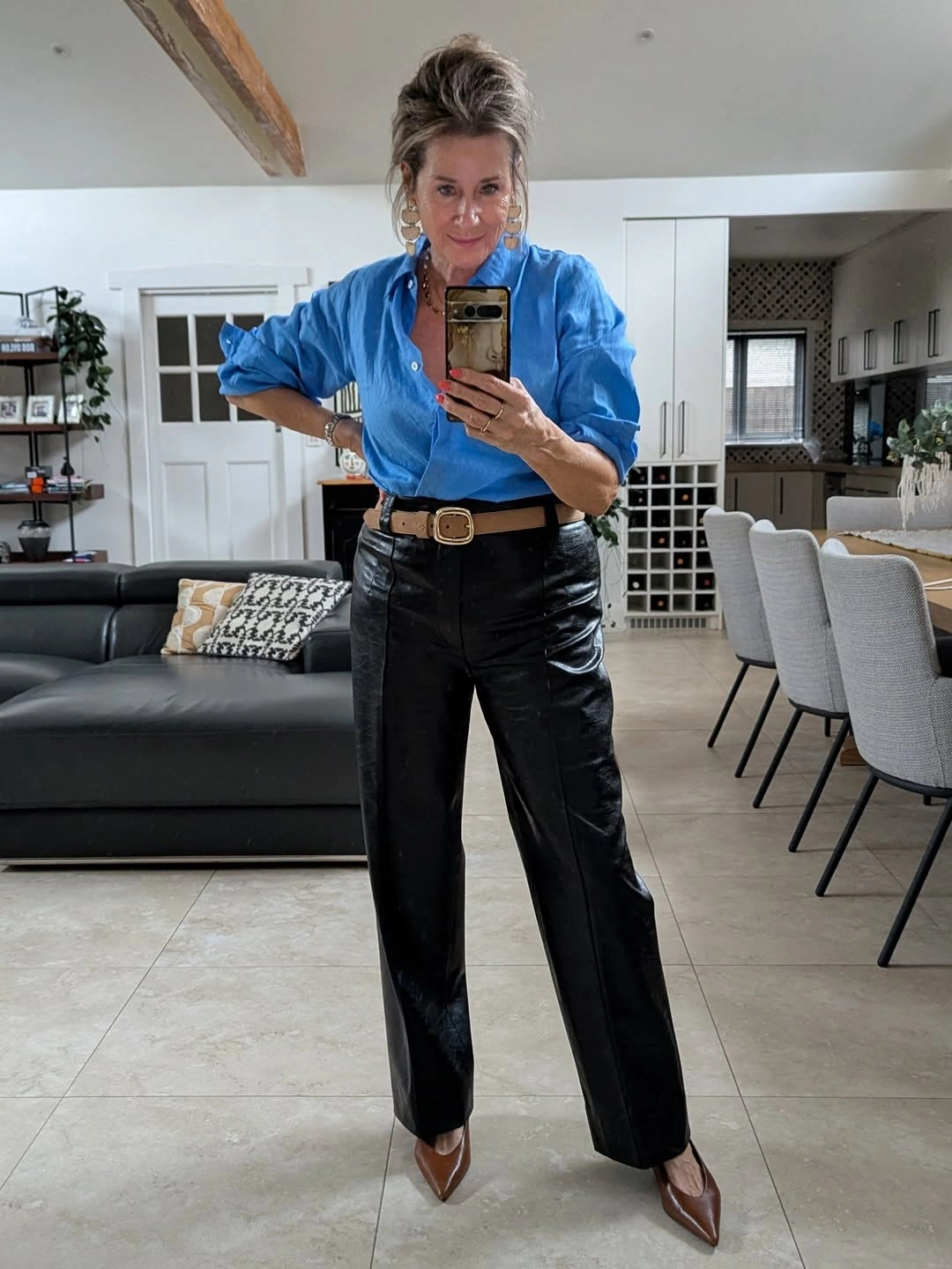 Blue button-down shirt with glossy black trousers and belt