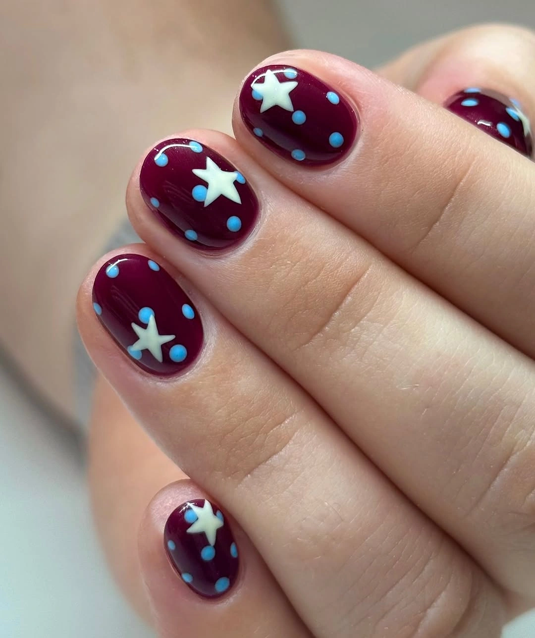 Short wine nails with white stars and blue dots