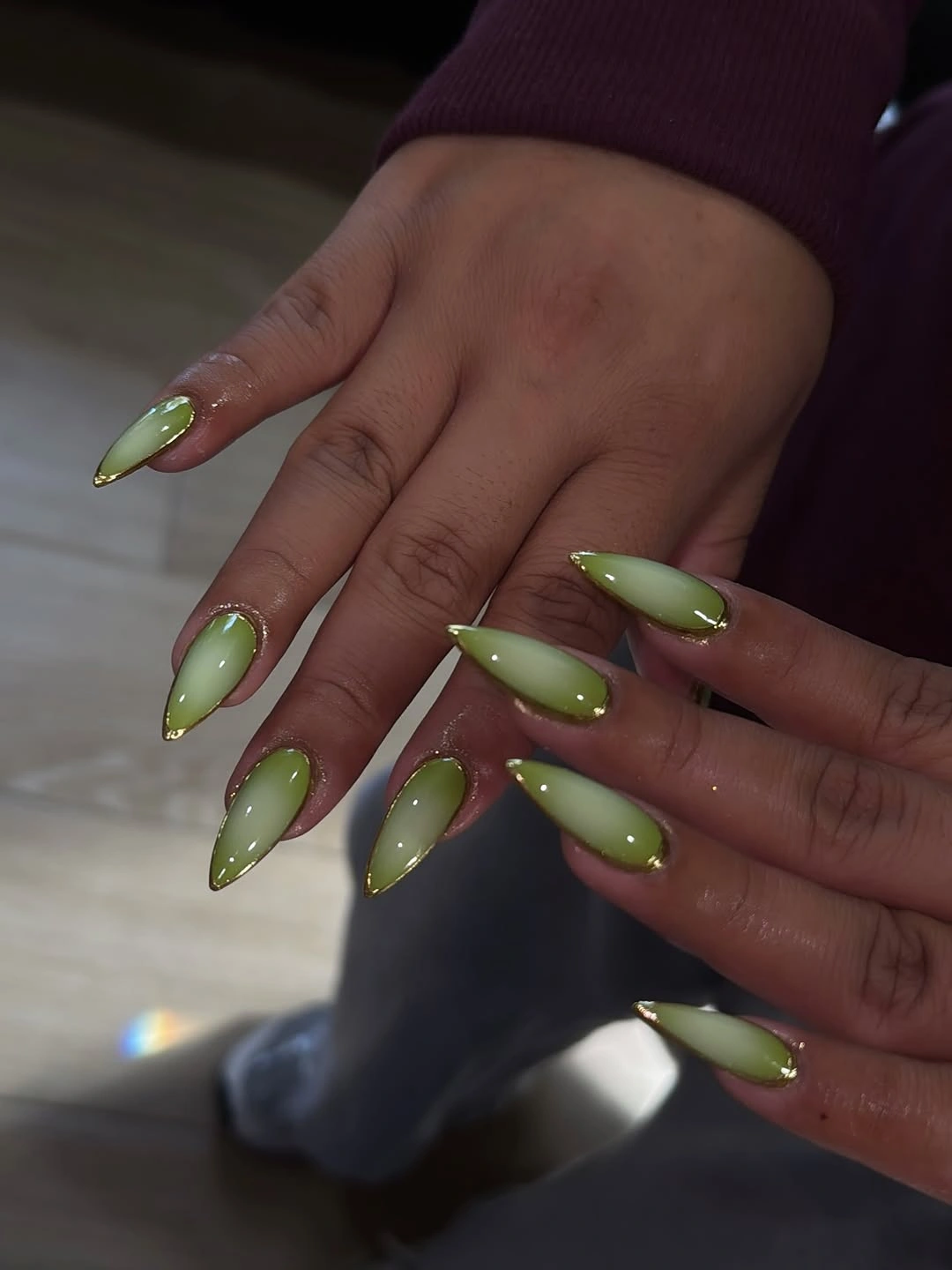 Light green almond nails with dots and gold-colored tips