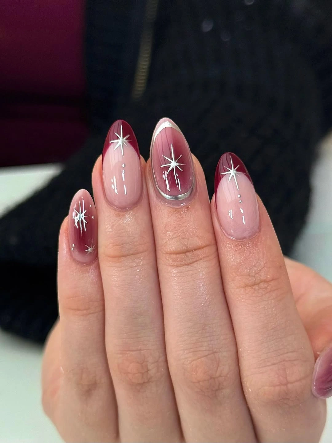 Almond nails with burgundy French tips and white starbursts