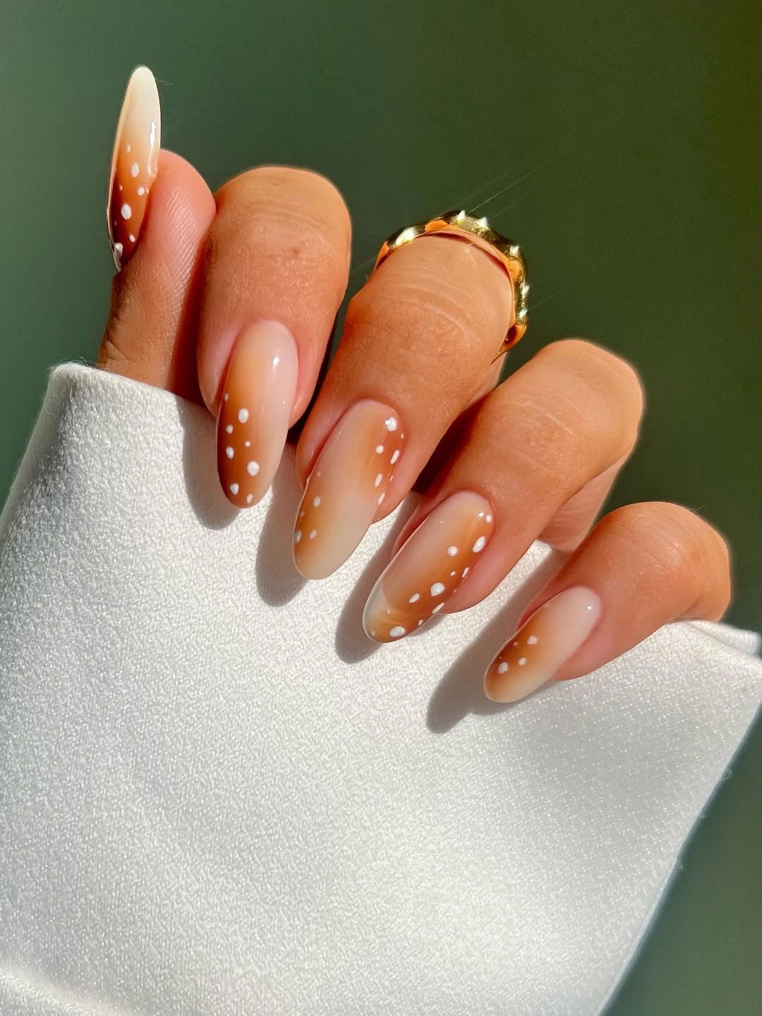 Nude almond nails with brown tips and white dots