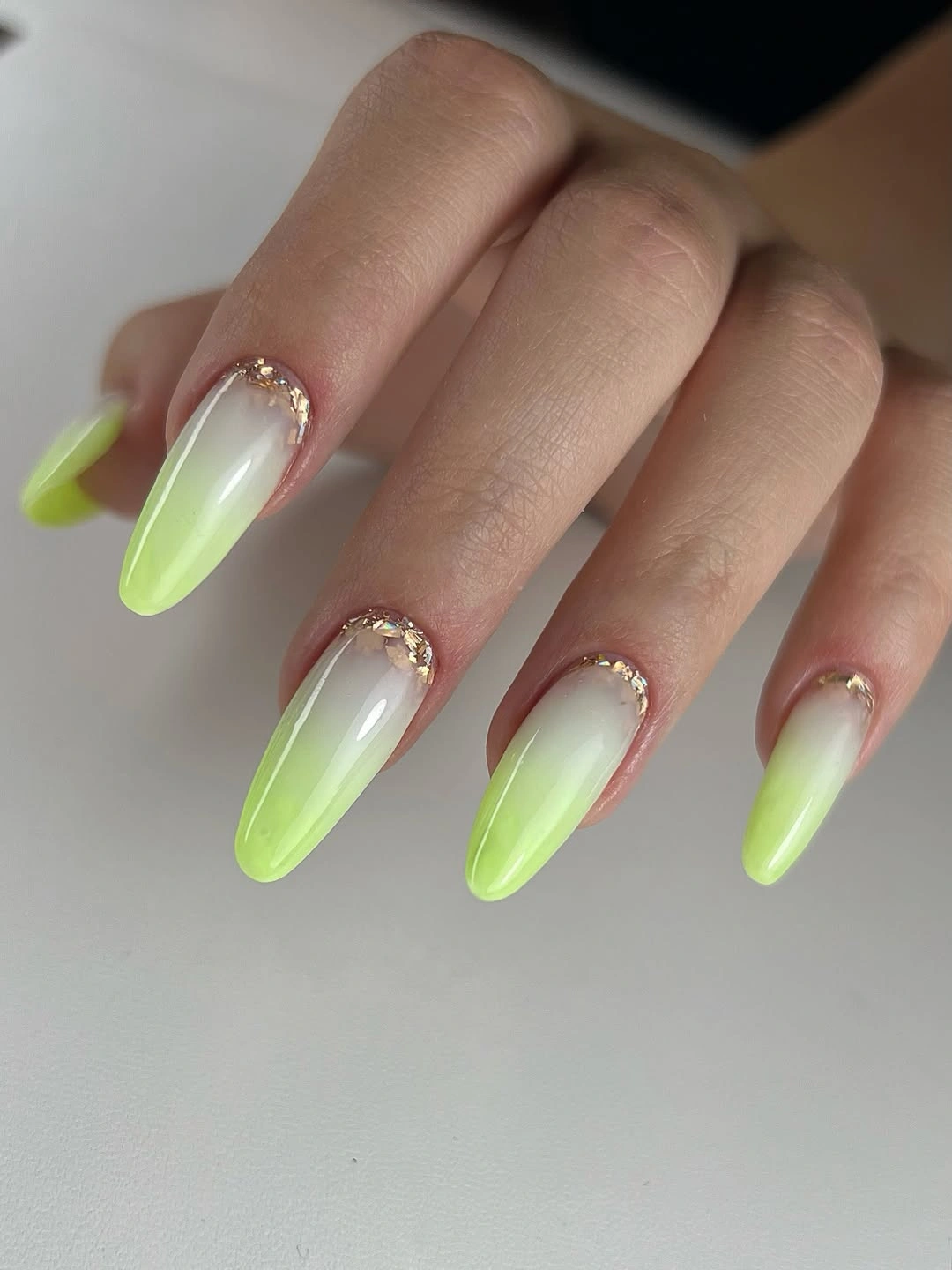 Pale green almond nails with white gradient and gold-colored cuticle accents