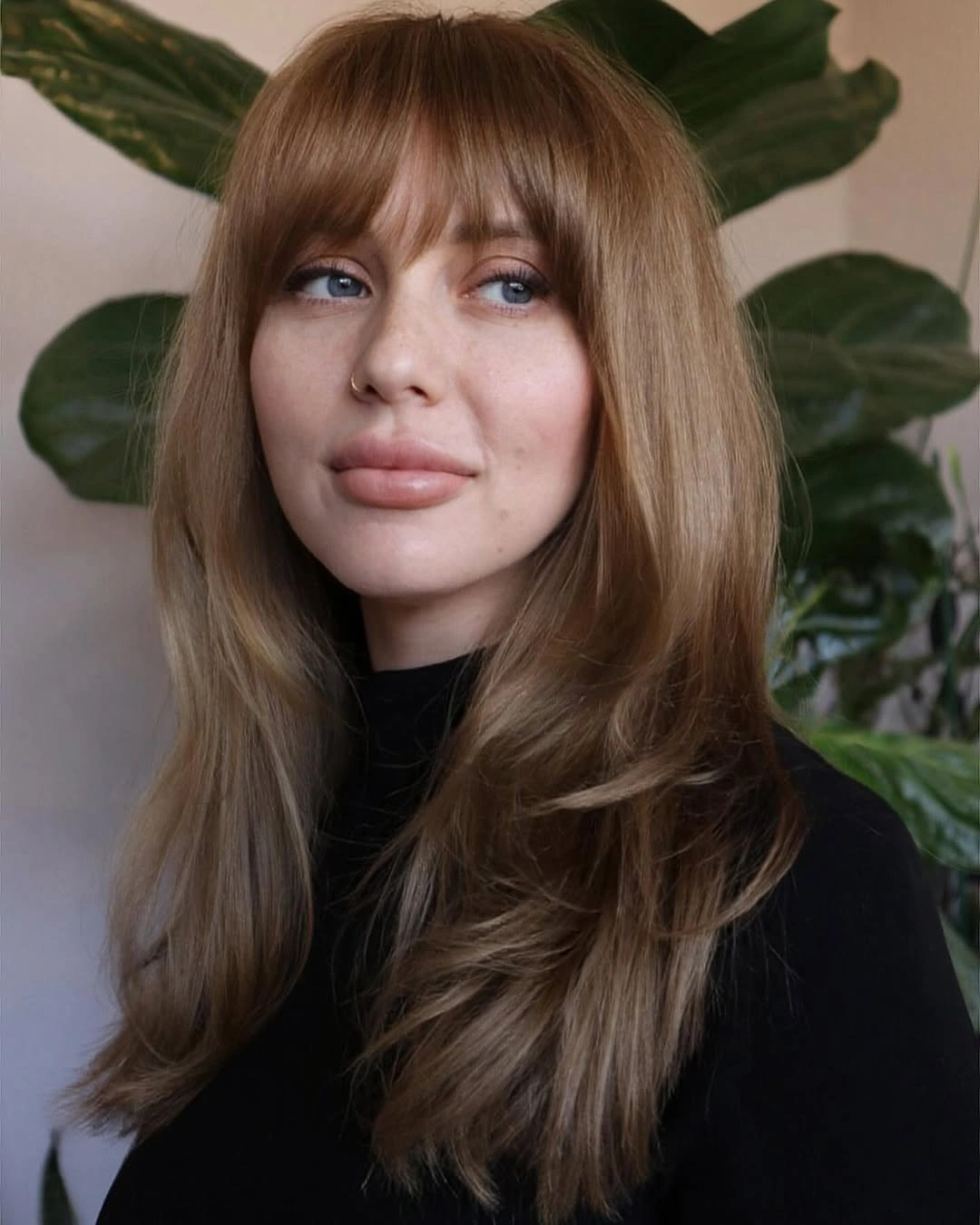 Long light brown layers with full bangs and black high neck