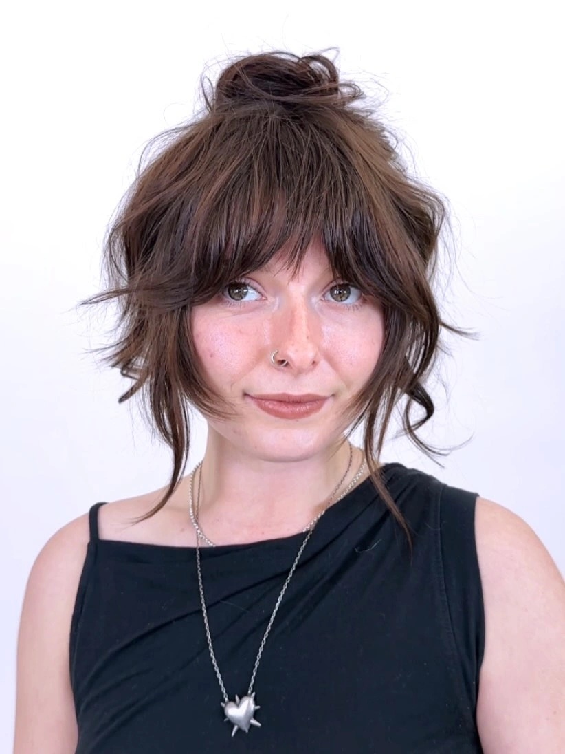 Dark brown bangs with high bun and loose face-framing pieces