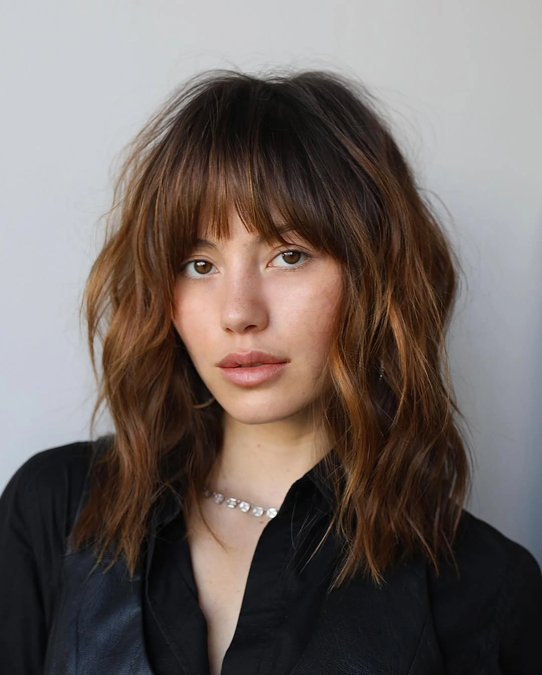 Medium brunette shag with bangs and caramel-highlighted waves