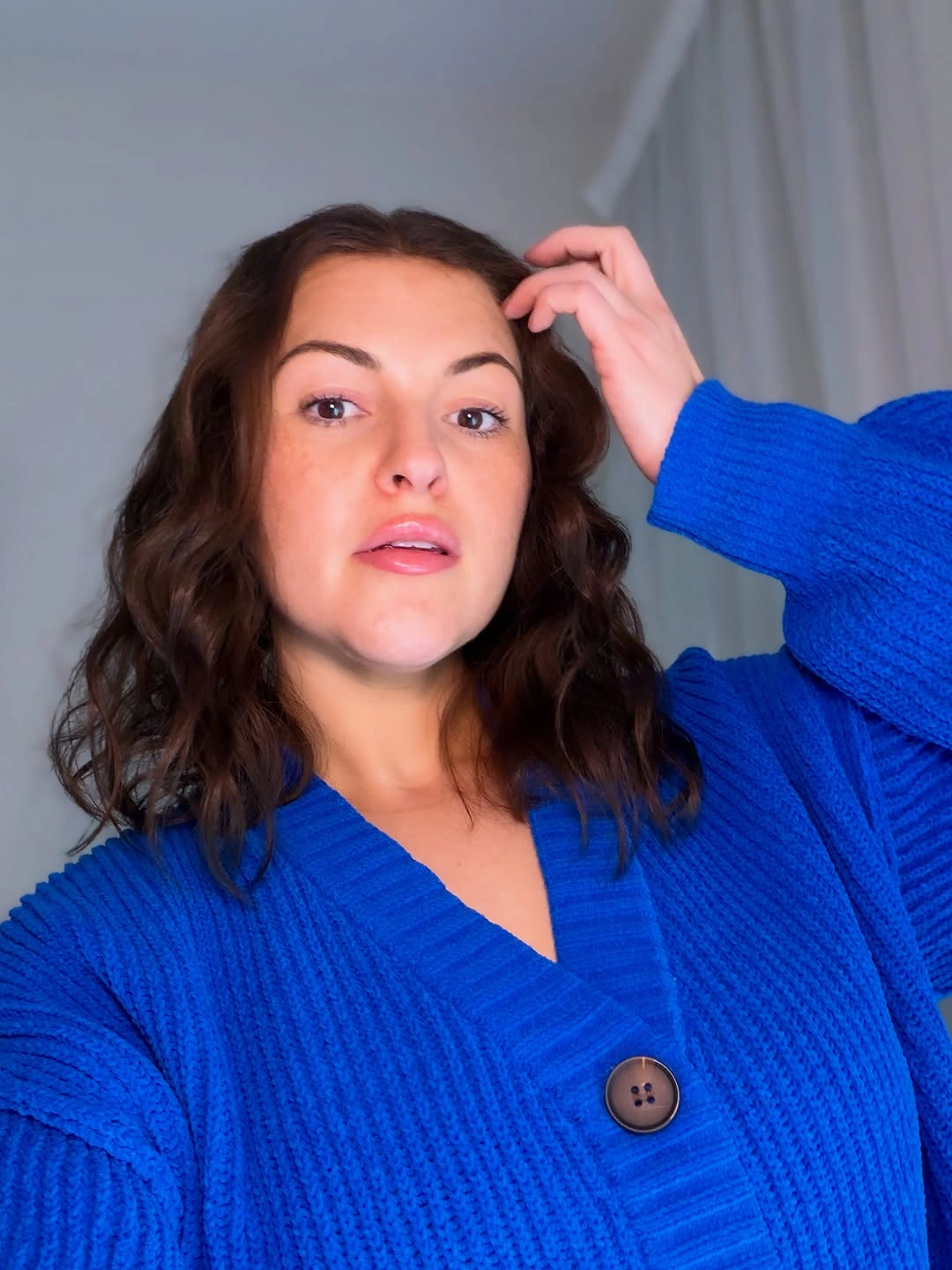 Shoulder-length brunette waves with blue ribbed cardigan