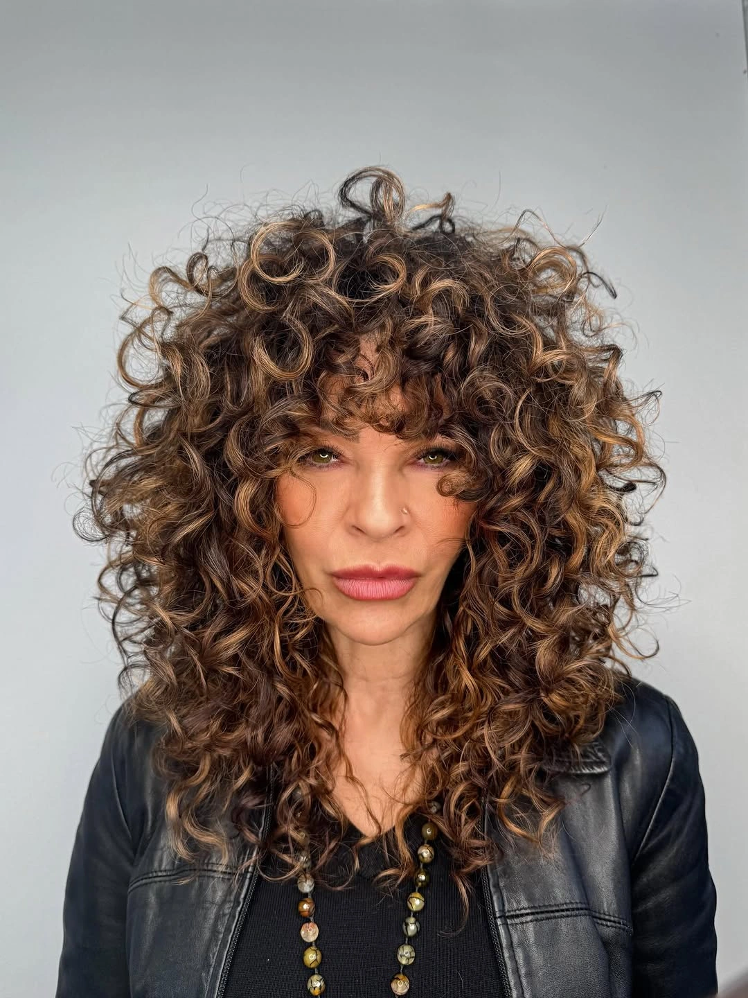 Highlighted curly shag with bangs and black jacket
