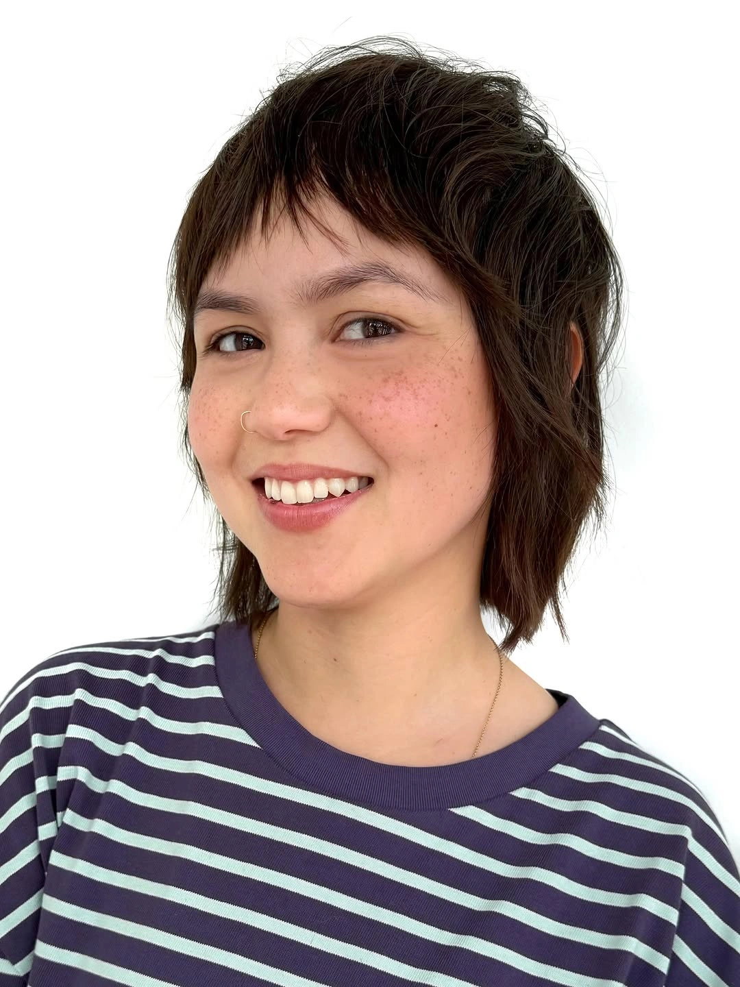 Short brunette textured cut with tiny bangs and striped shirt