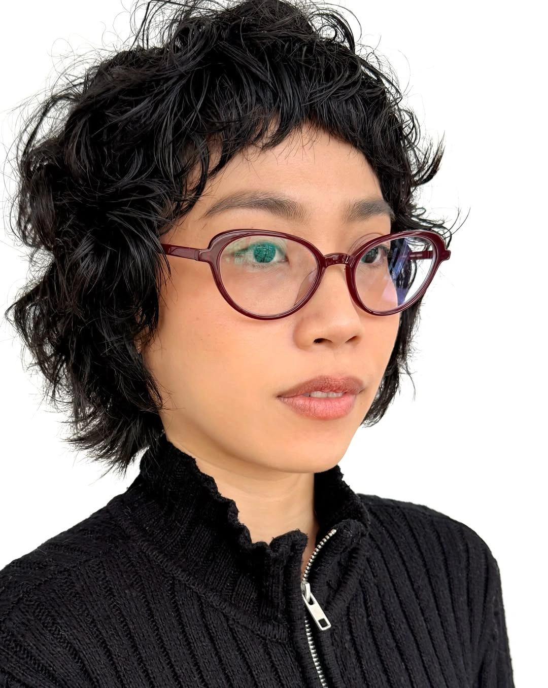 Short black curly crop with tiny bangs and red glasses